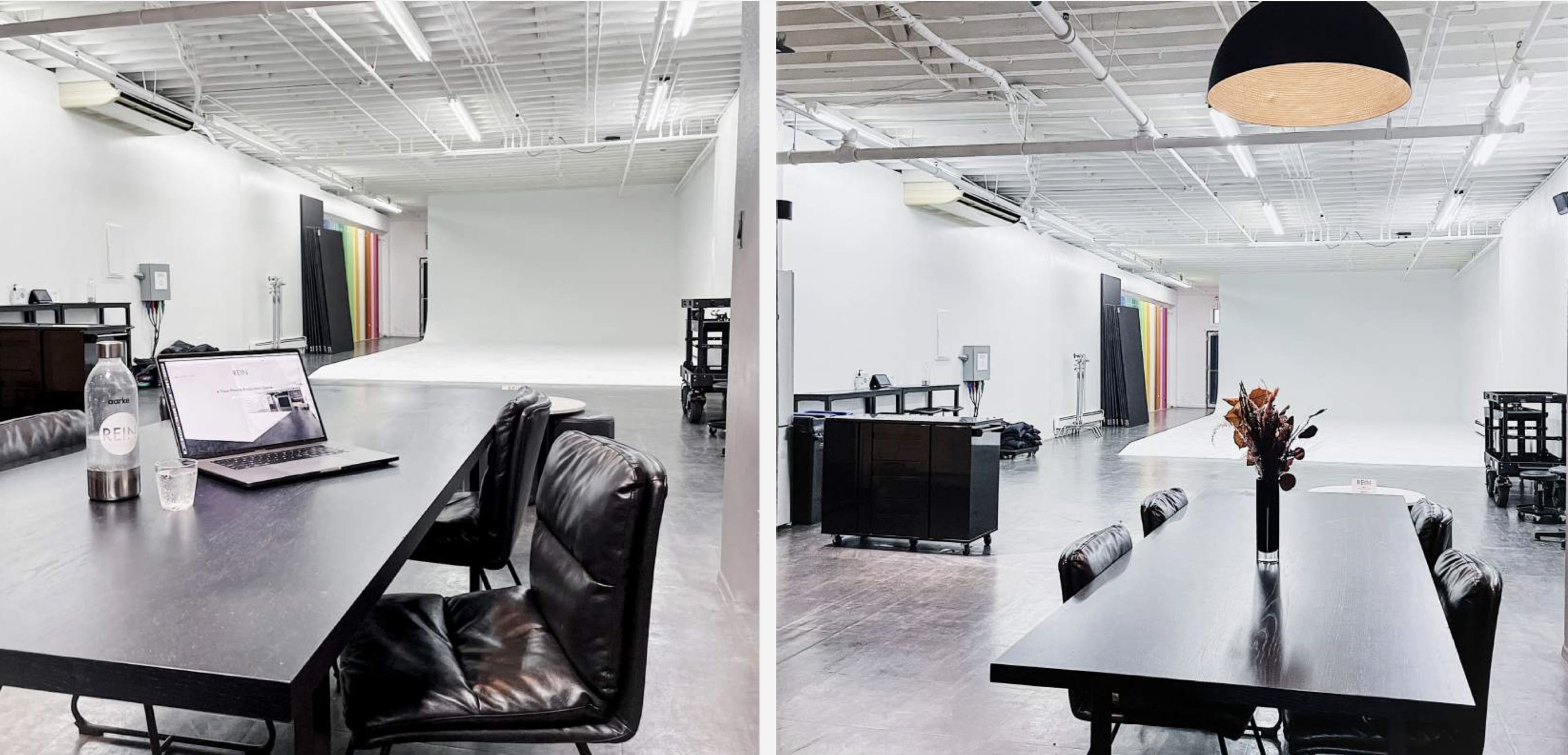 A spacious, well-lit studio with a long prep table and a backdrop setup in the corner.