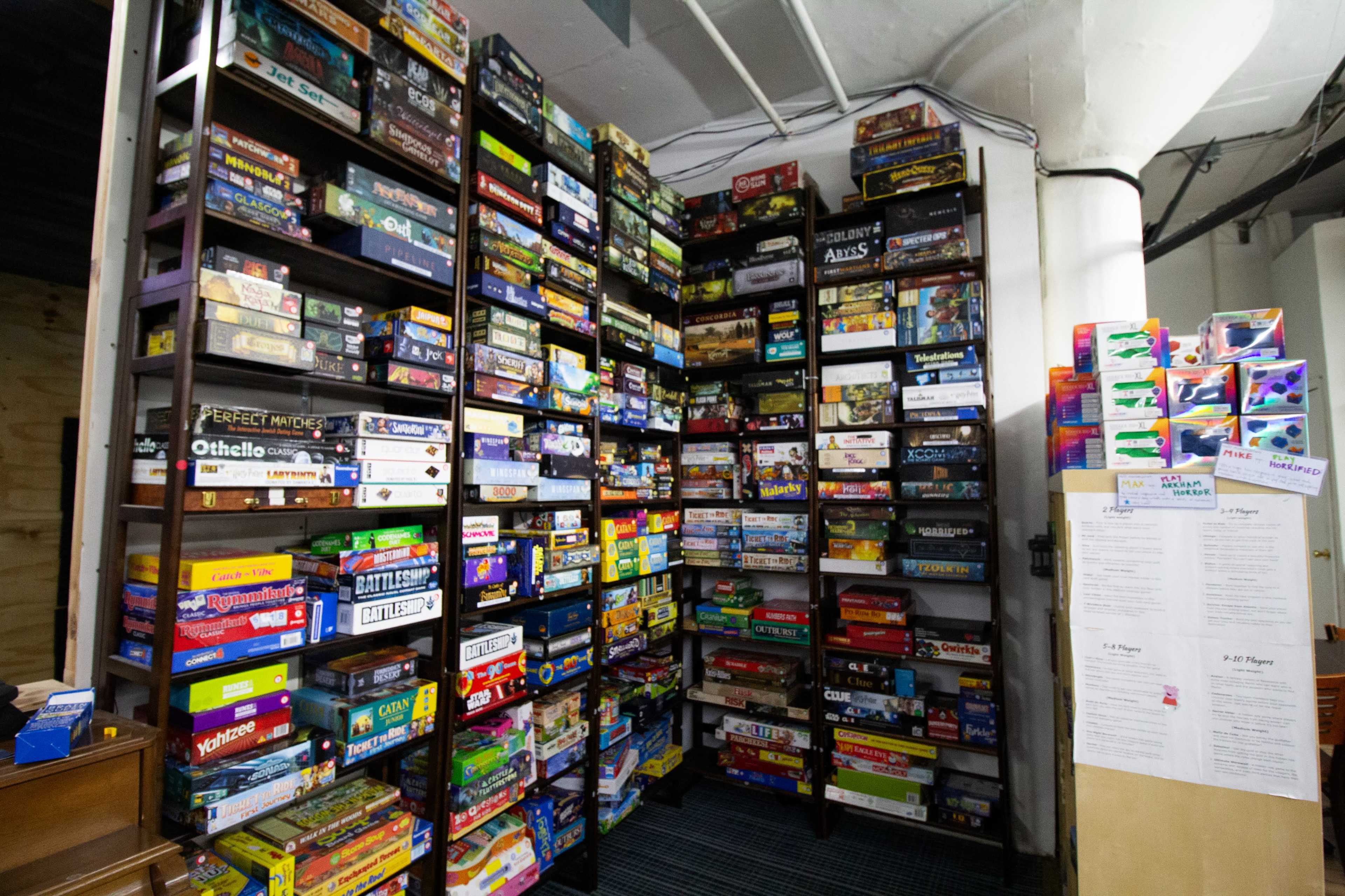 A large bookshelf stacked with a variety of board games arranged neatly on multiple shelves.