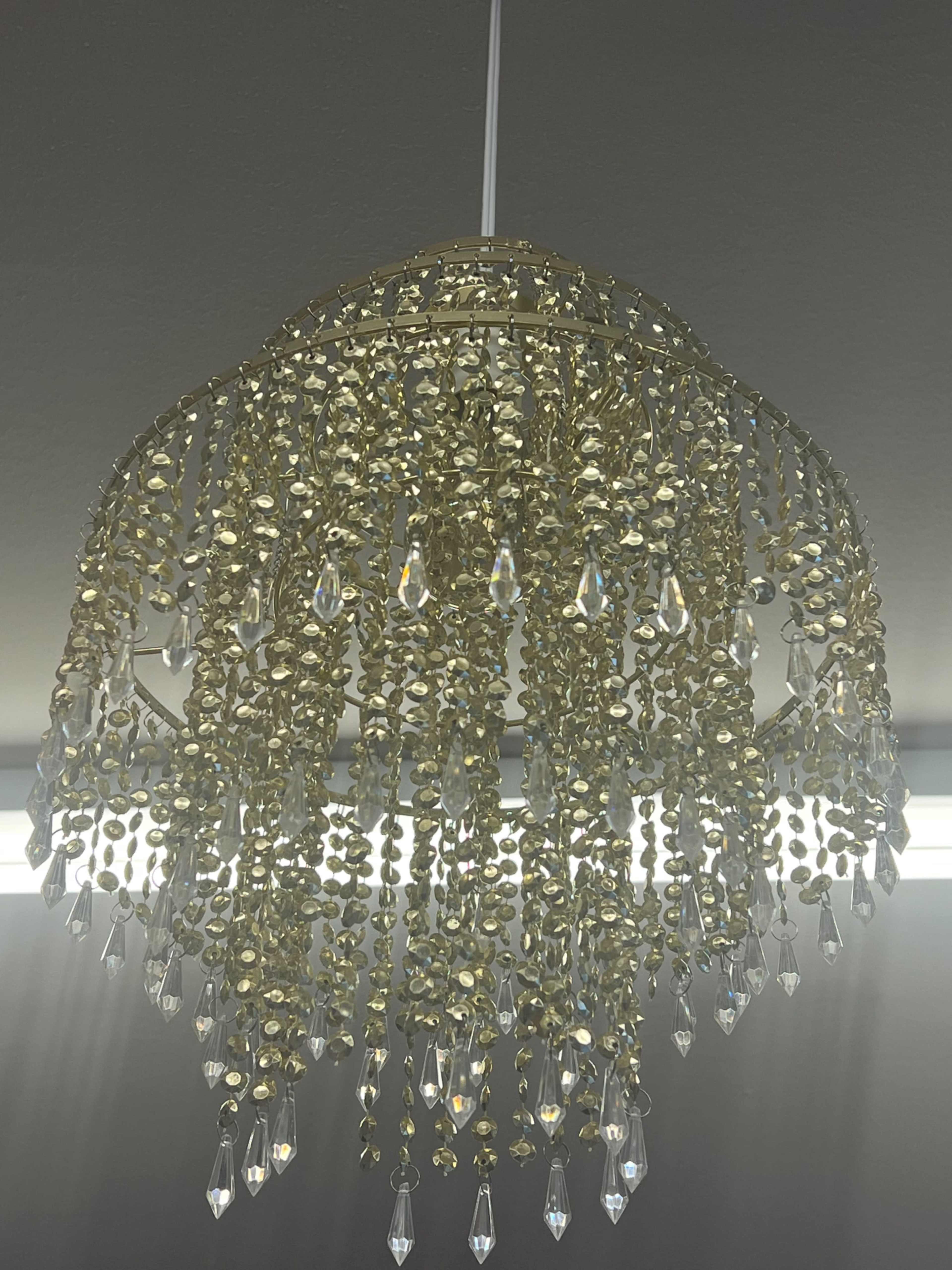 A gold-colored chandelier adorned with hanging crystal droplets.