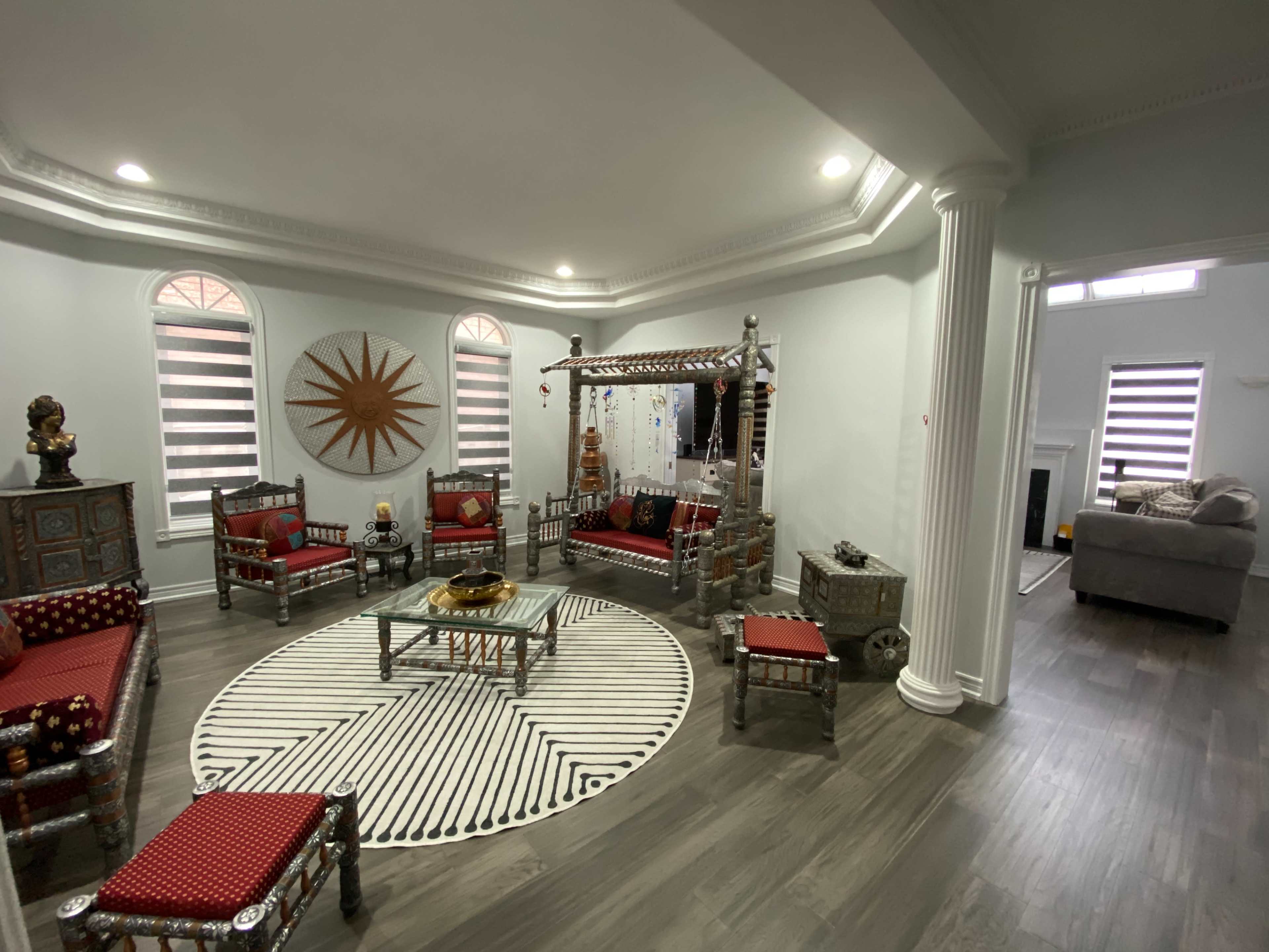 The room features a decorated seating area with silver-framed furniture arranged around a circular rug and a coffee table.