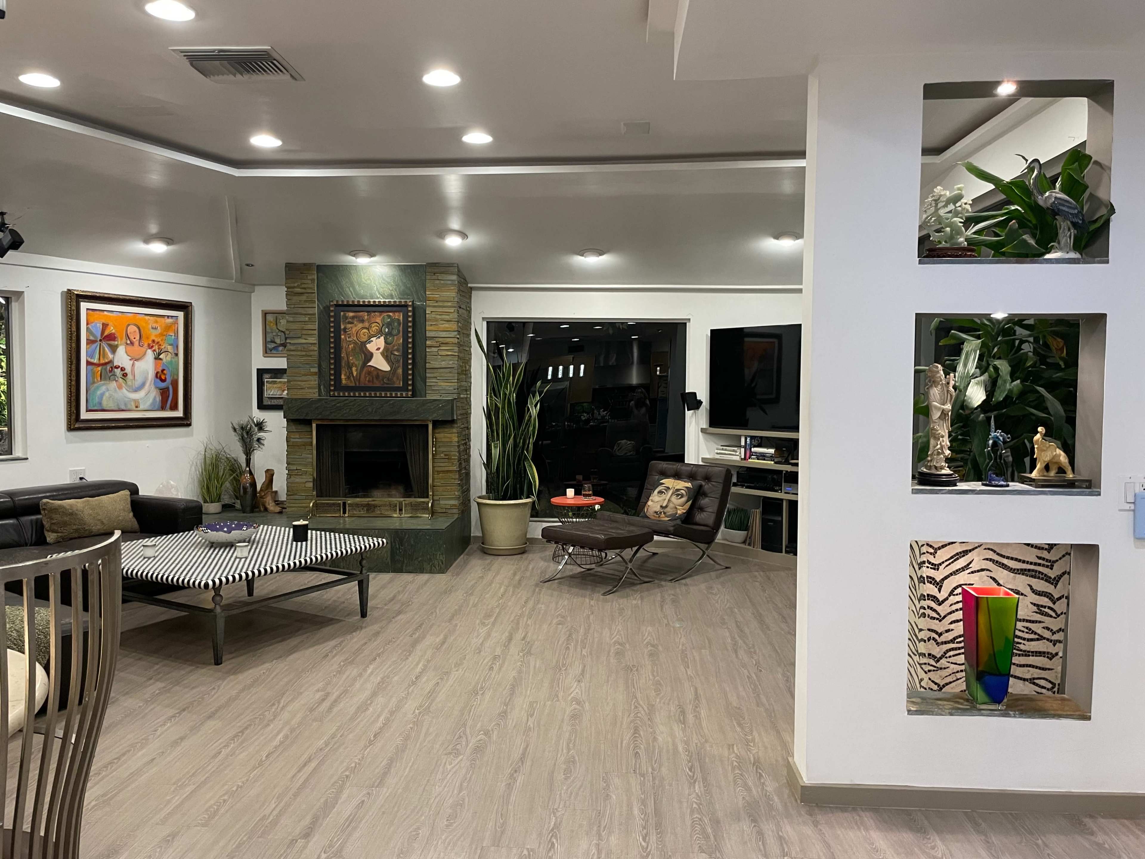 A modern living room with a fireplace, art on the walls, and a mix of furniture including a sofa and lounge chairs.