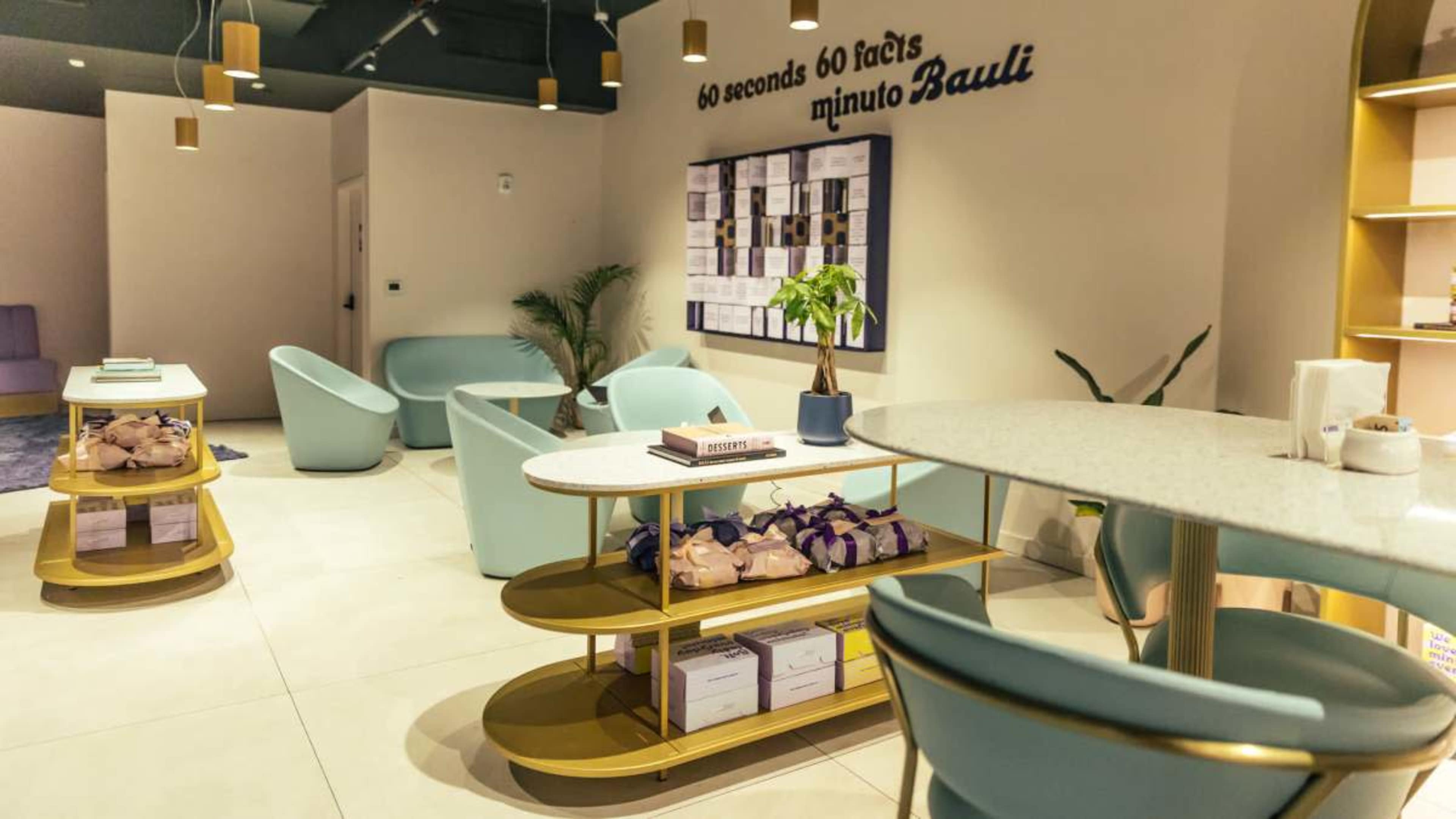 The image shows a modern, minimalistic interior design of a seating area with light-colored walls, a round table, and stylish chairs in pastel colors.