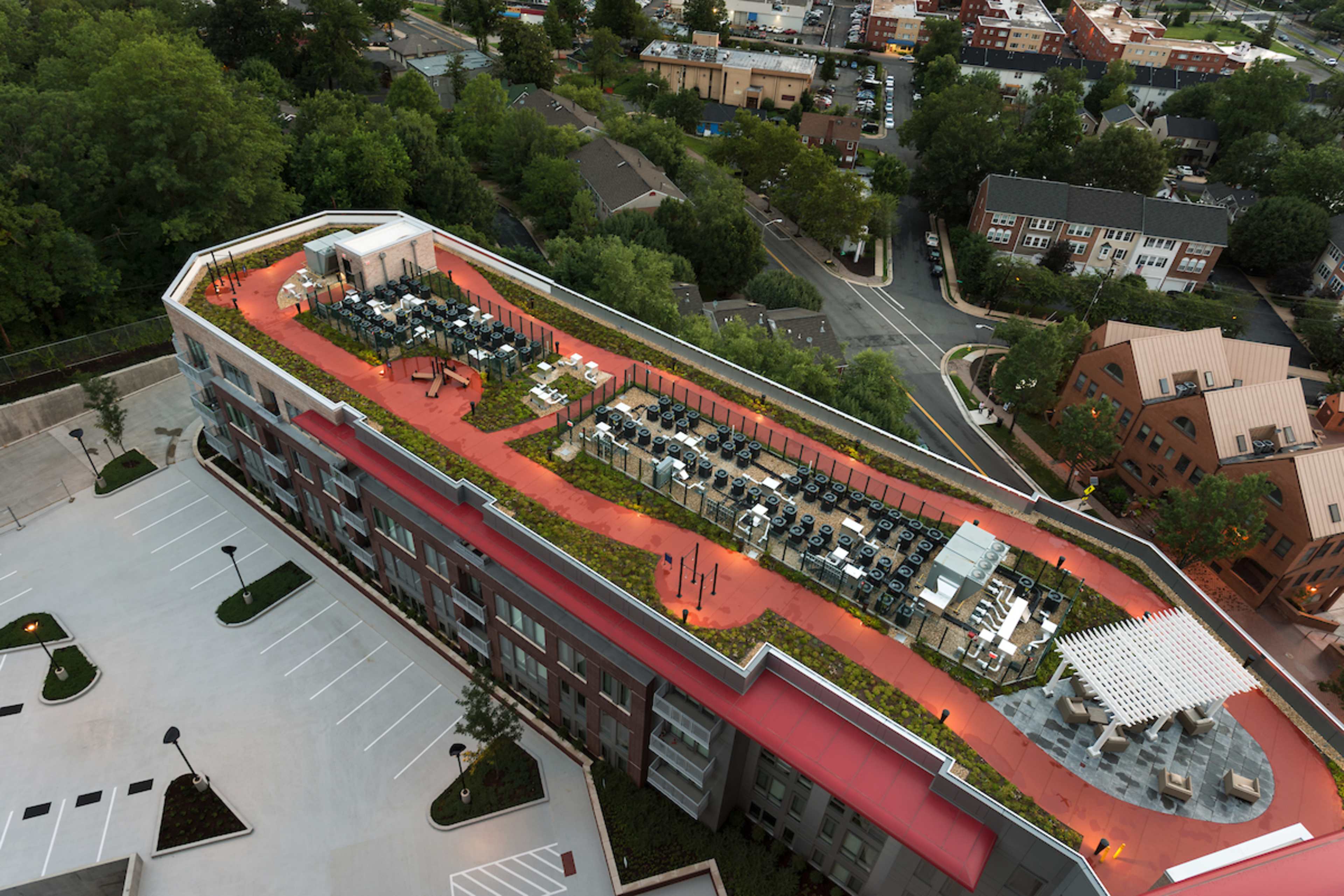 An aerial view of a modern building with a landscaped rooftop terrace featuring seating areas and greenery.