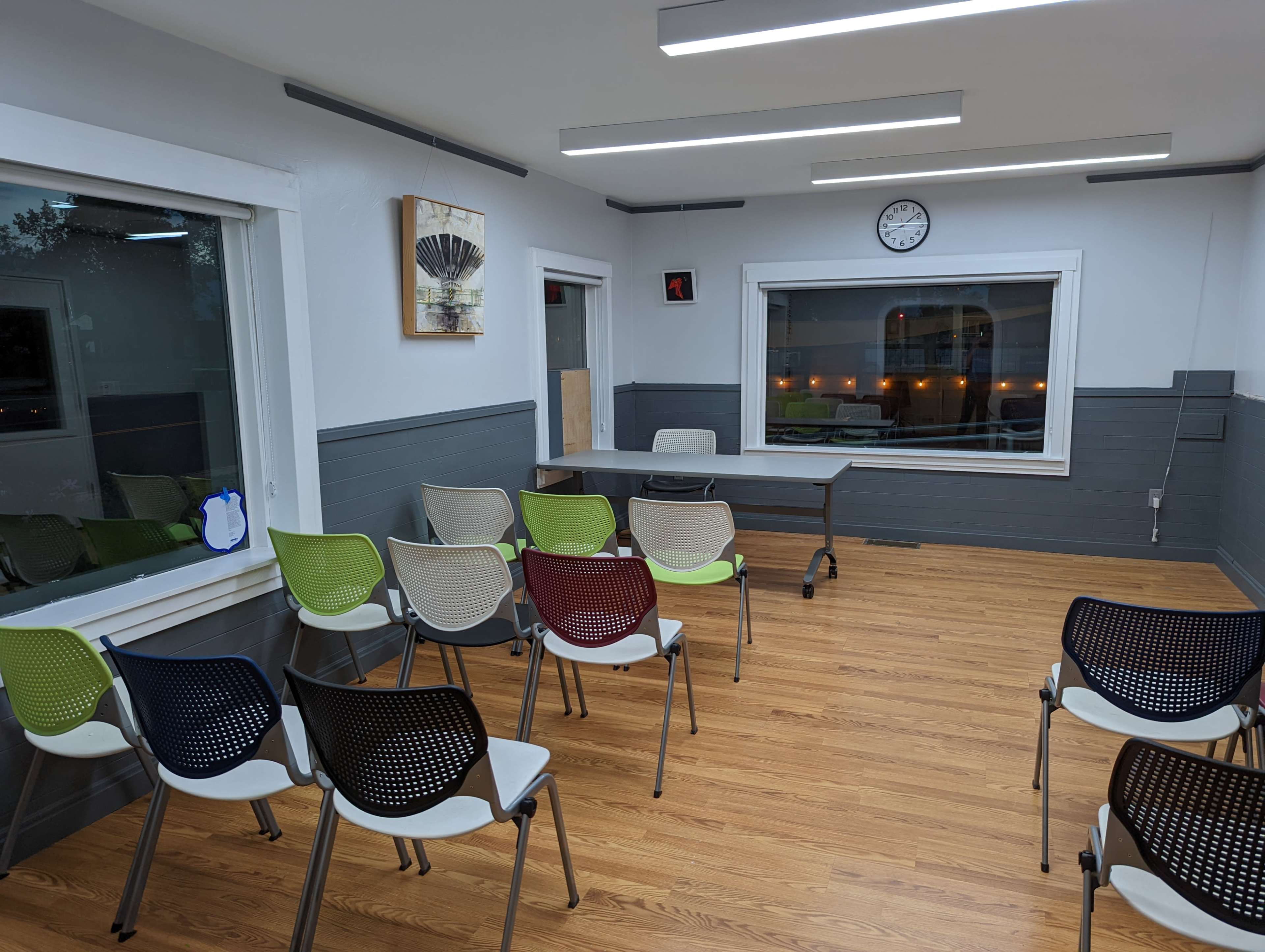 A meeting room is set up with a long table at the front and empty chairs arranged in rows facing it.