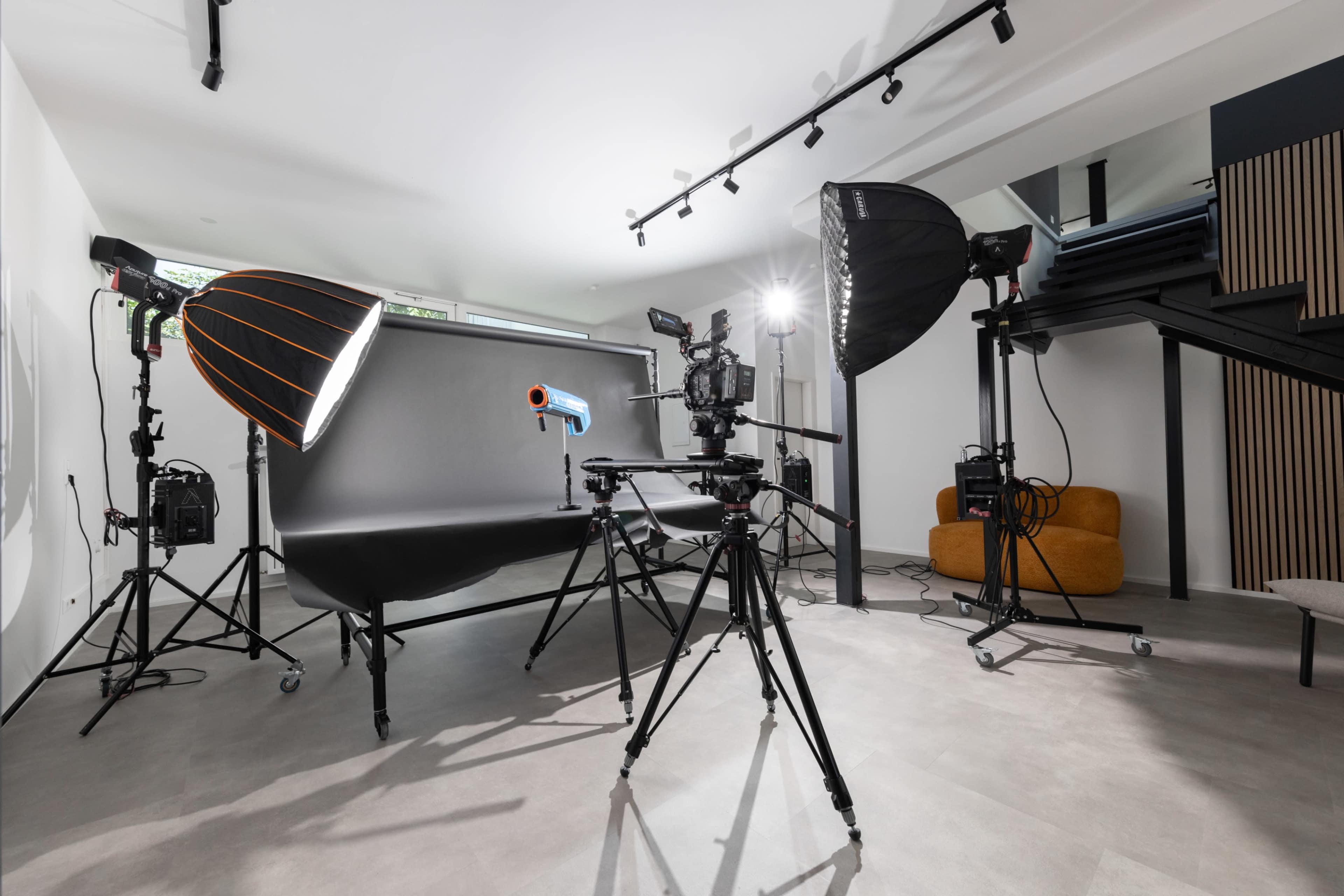 The image shows a photography studio setup with various lighting equipment and a camera mounted on a tripod.