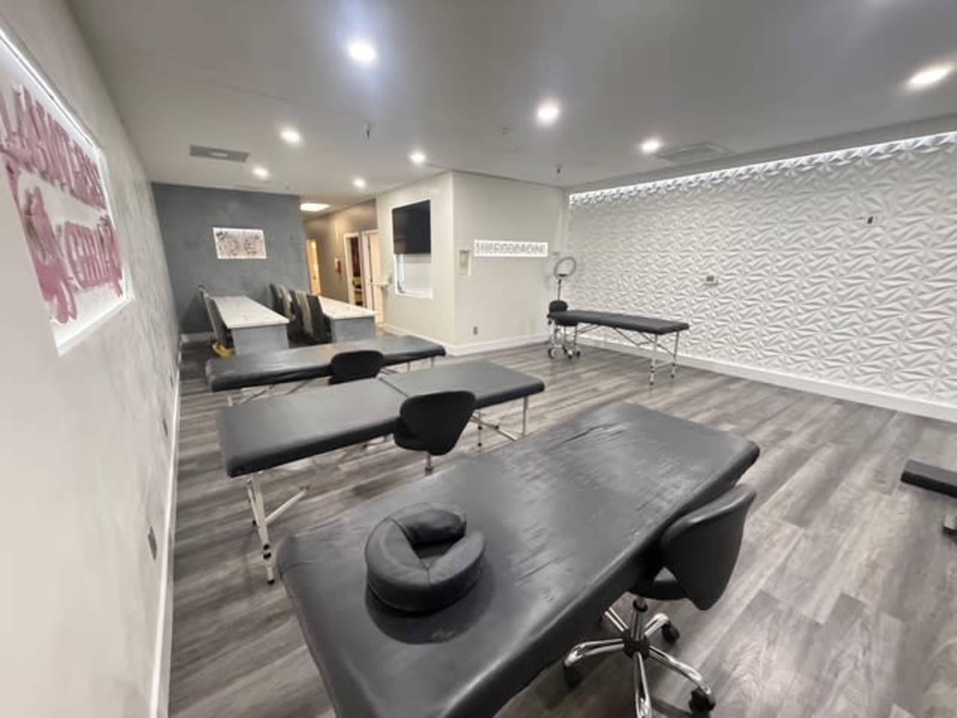 The image shows a clean and modern treatment room with several examination tables arranged in a spacious layout.