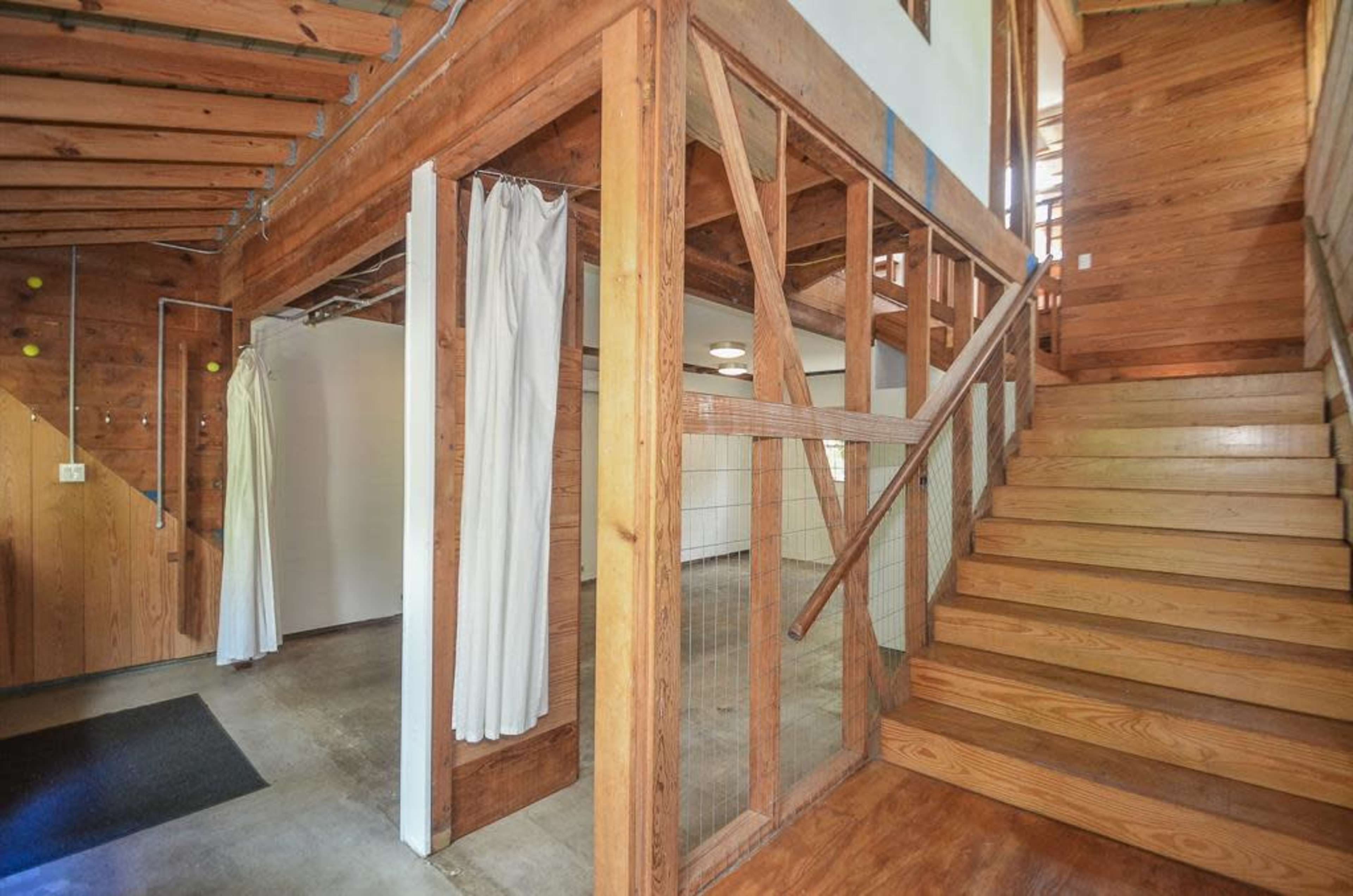 The image shows a wooden interior of a modern home featuring an open layout with a staircase leading to the upper level.