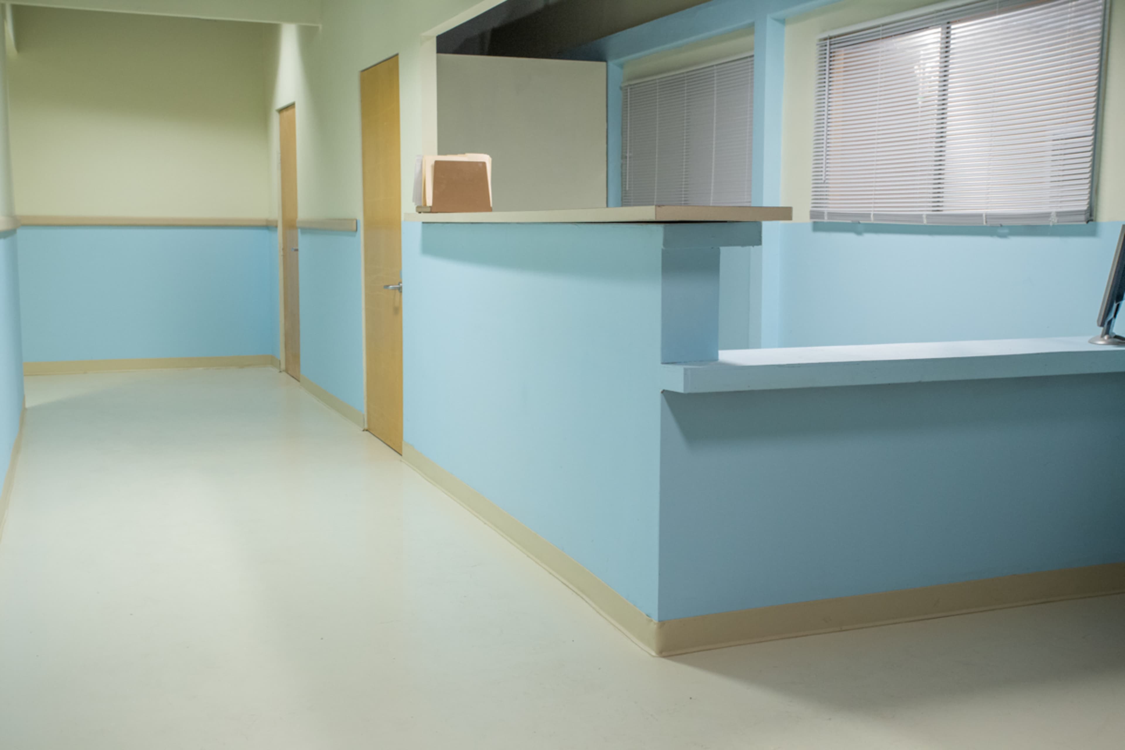 A brightly colored hallway in a medical facility with light blue and green walls and an empty reception desk.