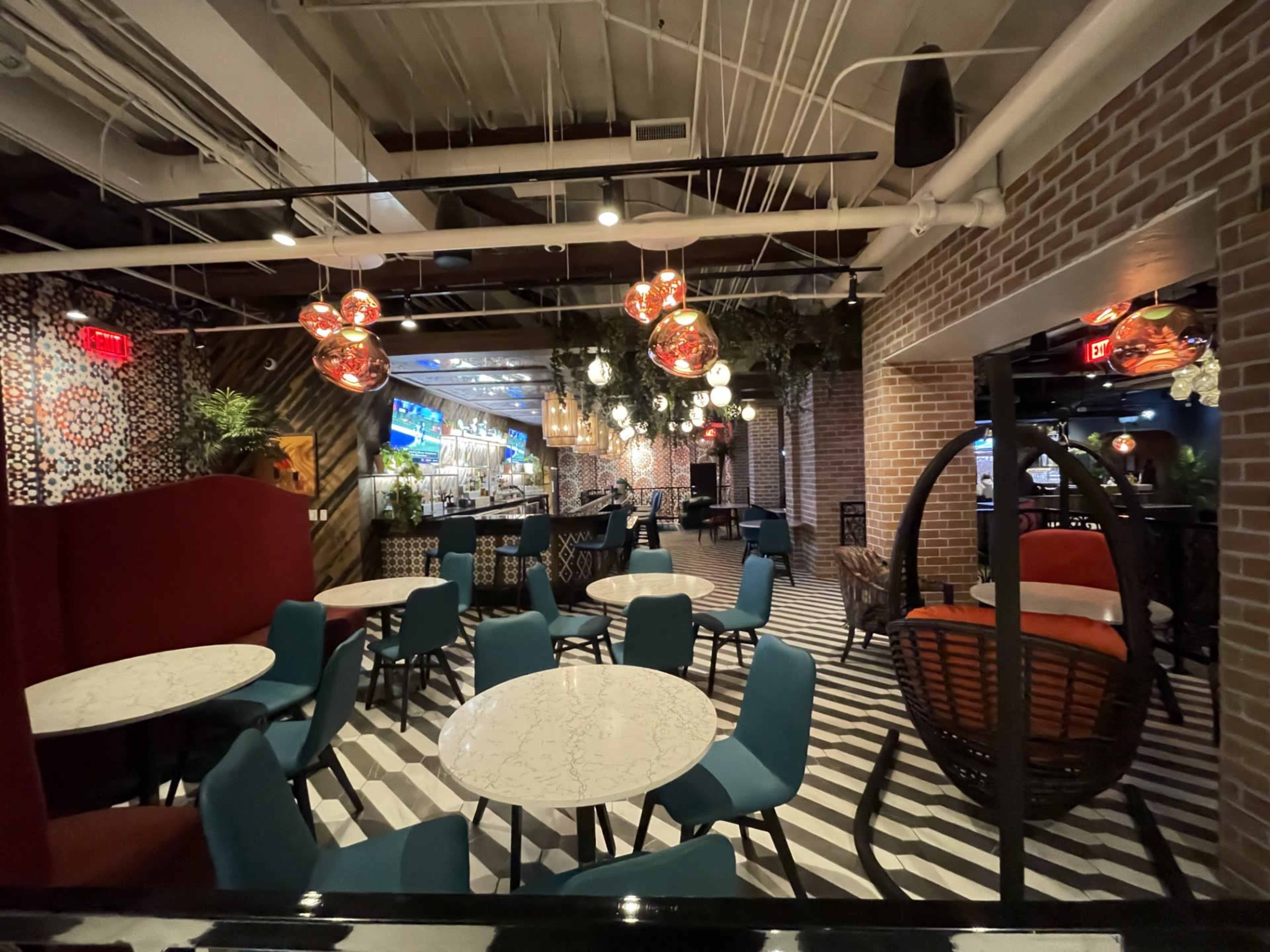 The image shows a modern restaurant interior with patterned walls, various seating arrangements, and decorative lighting fixtures.