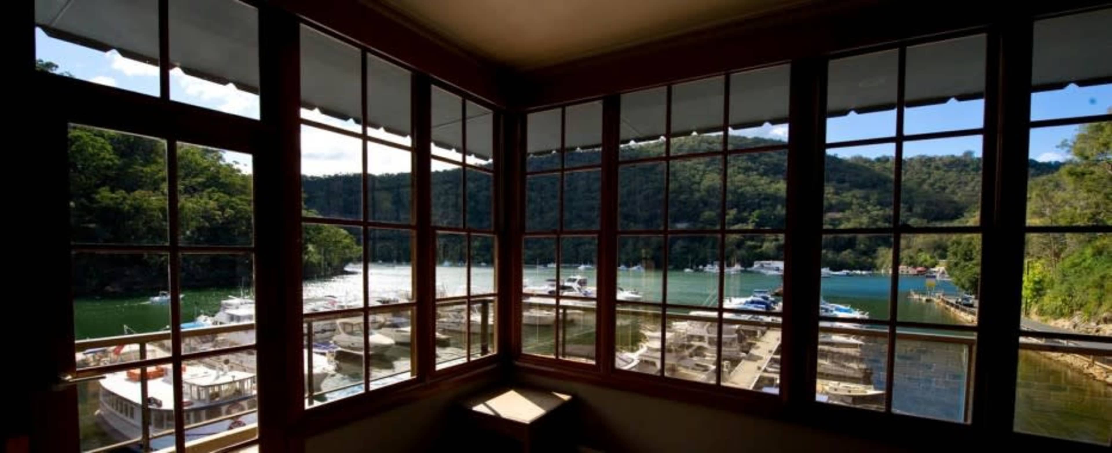 A view from a window overlooking a marina with boats docked along a green, wooded shoreline.