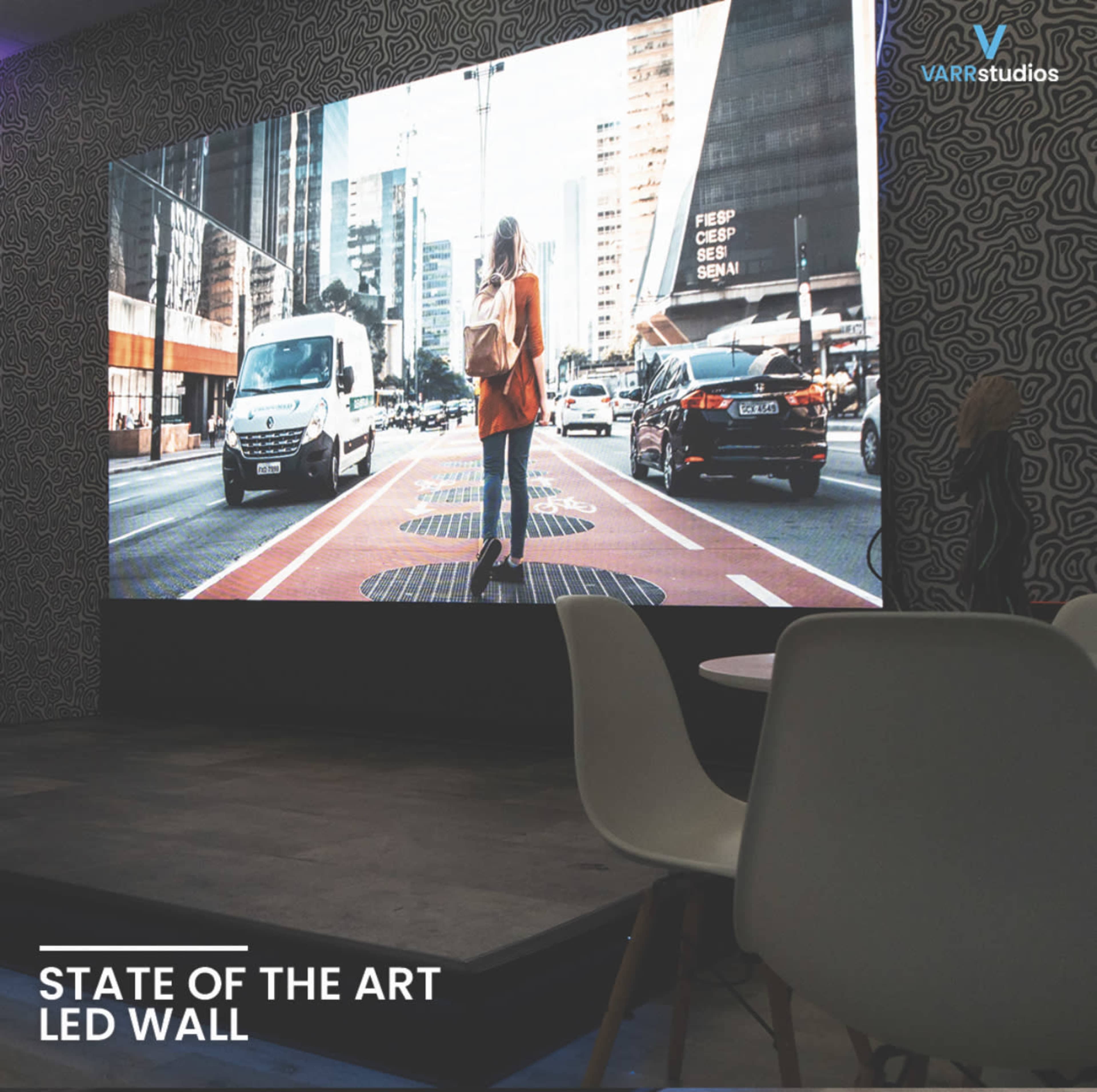 A large LED wall displaying a city street scene with a person walking amidst traffic.