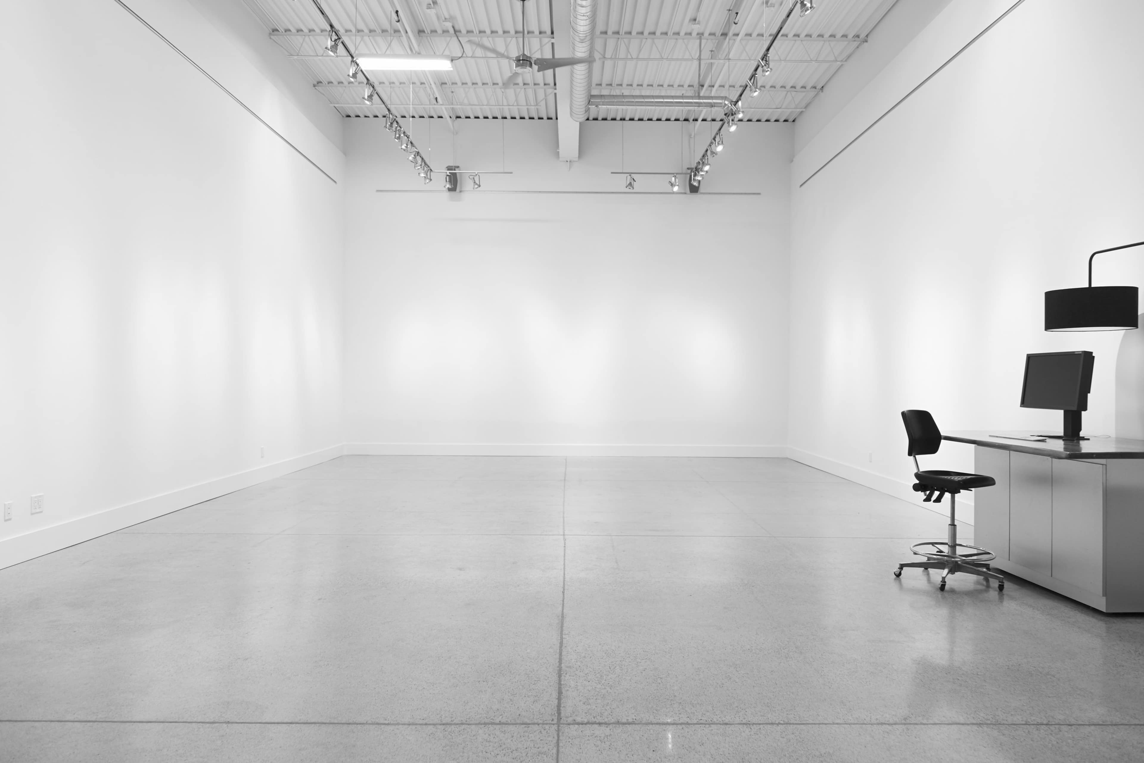 A minimalist office space with a desk and computer chair positioned against a stark, empty wall.