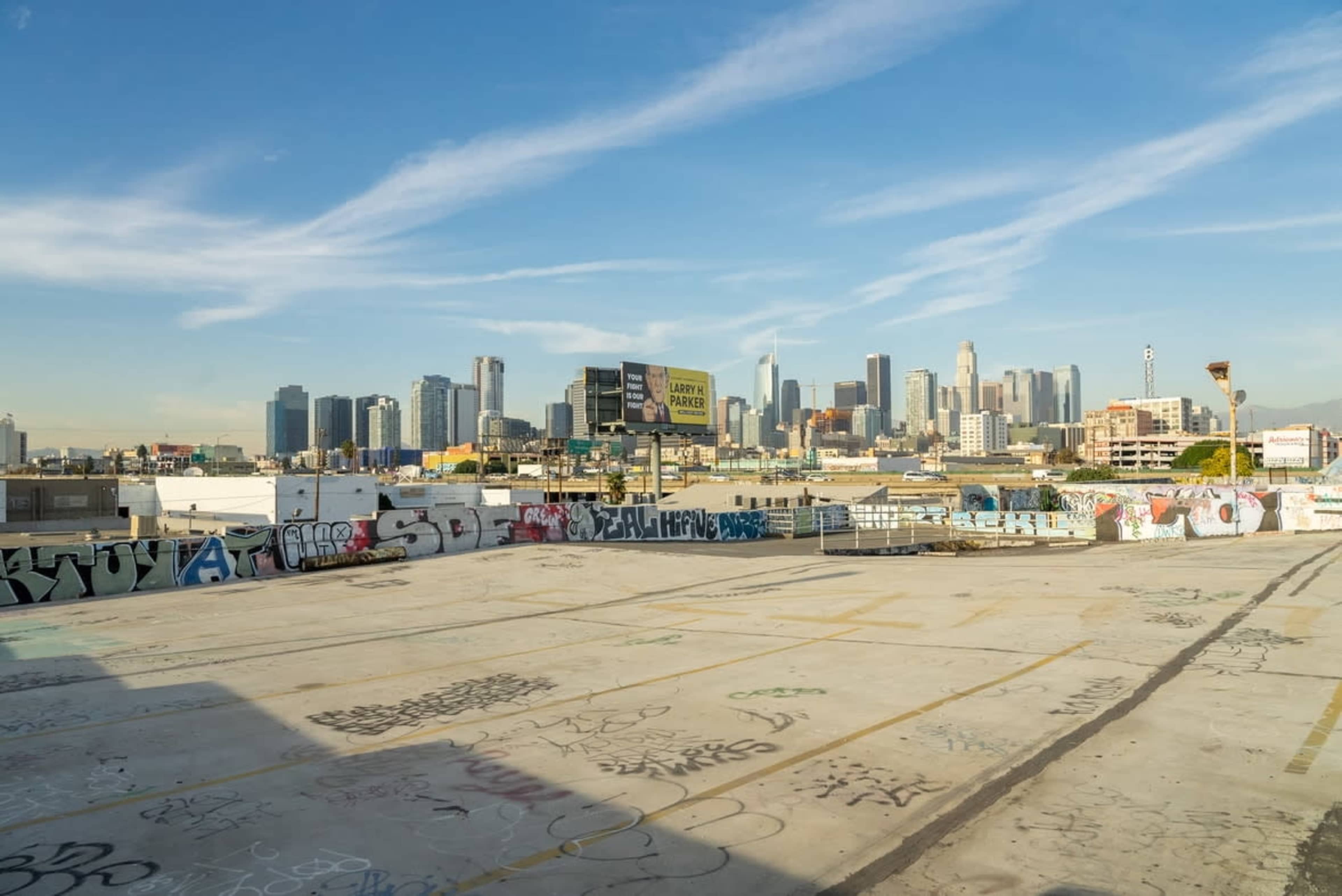 The image shows a rooftop view of a city skyline with skyscrapers and graffiti on surrounding surfaces.
