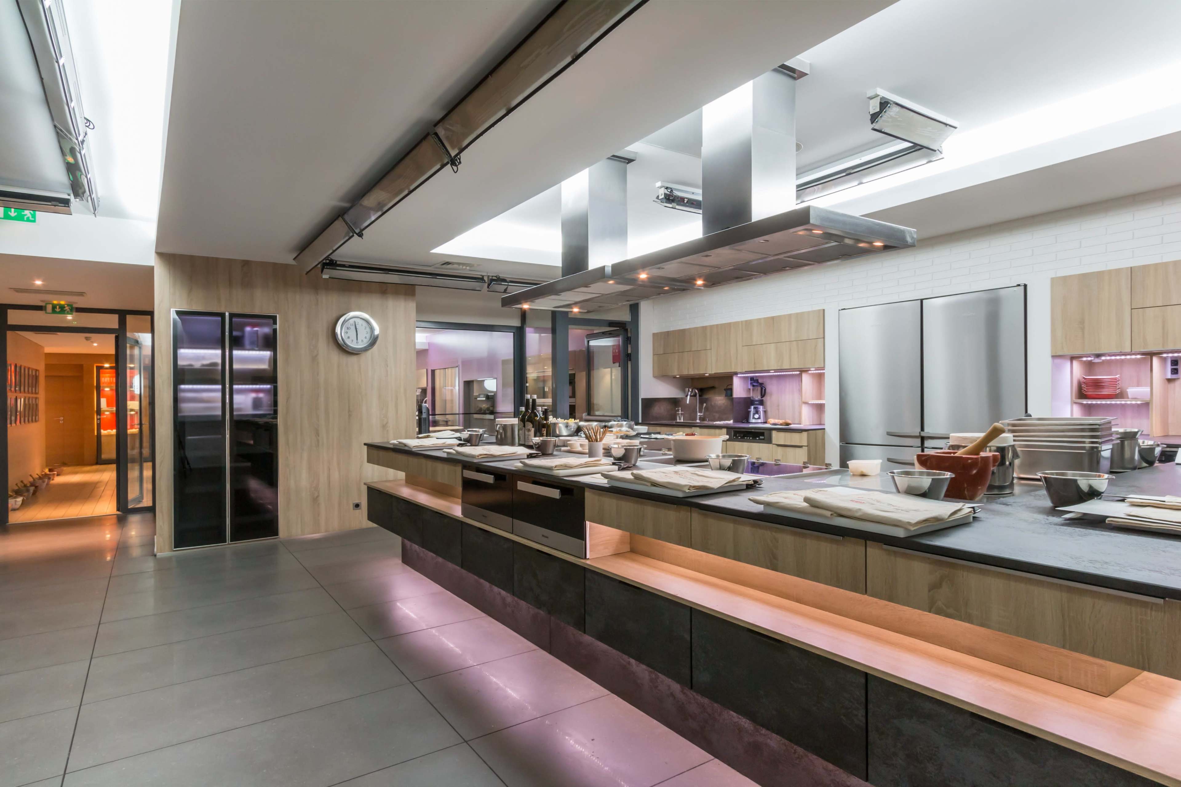 A modern kitchen with sleek cabinetry, stainless steel appliances, and a spacious island is illuminated by overhead lighting.
