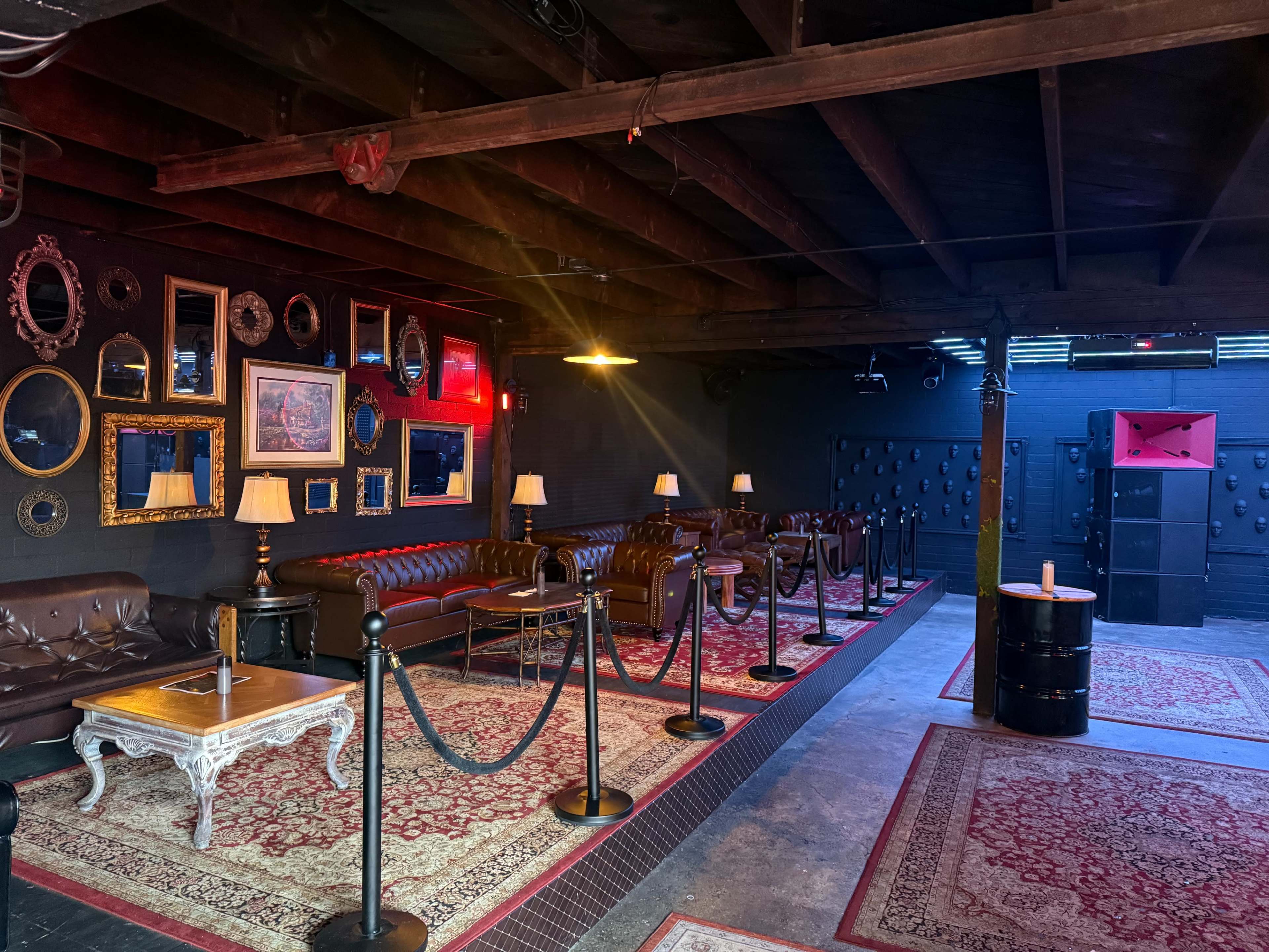 The image shows a dimly lit lounge area with leather seating, decorative mirrors on the walls, and a pattern of rugs on the floor.