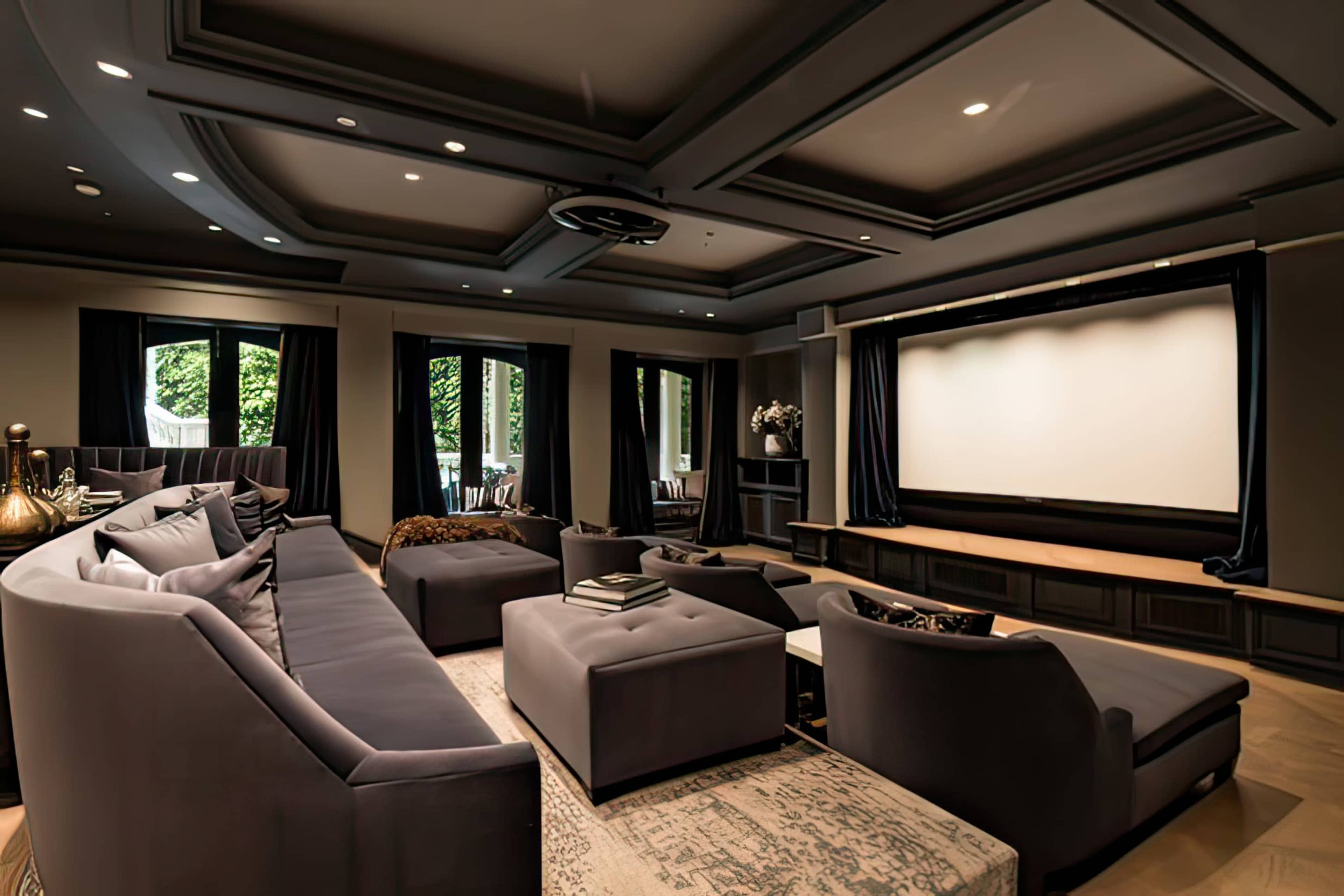 A modern home theater with dark furnishings, a large screen, and windows covered by curtains.