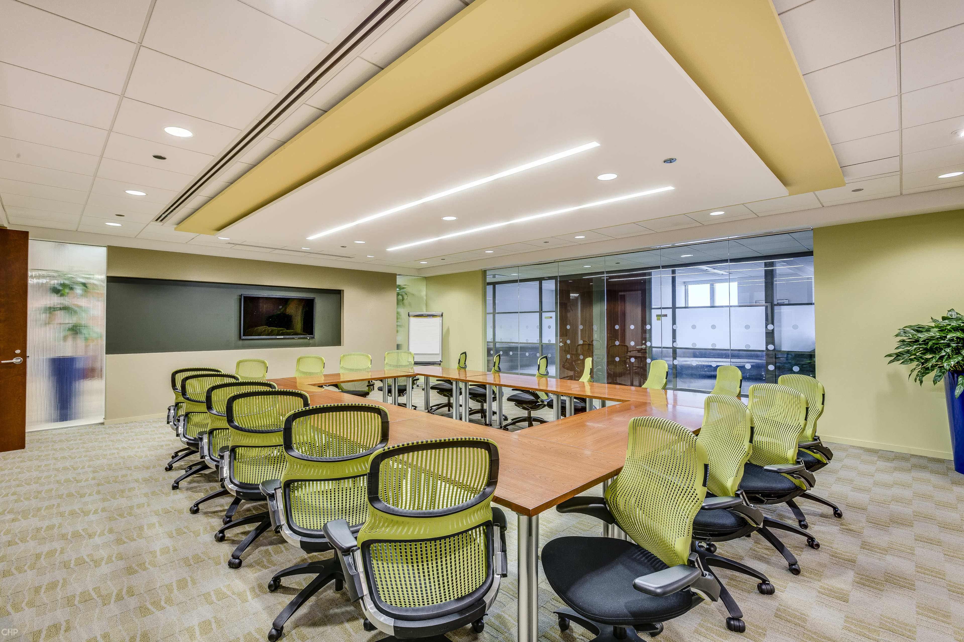 A modern conference room with a large rectangular table surrounded by ergonomic chairs and glass walls.