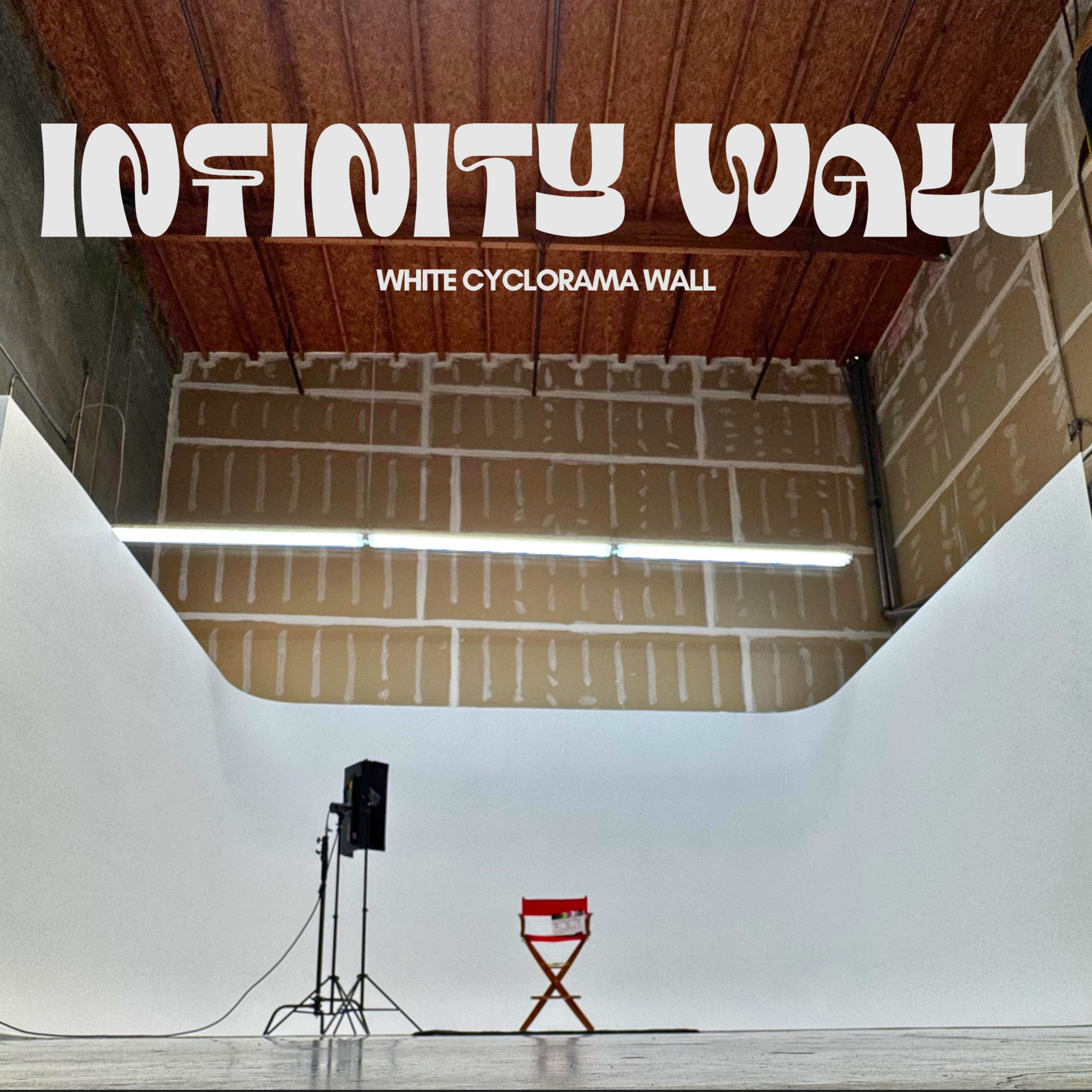 The image shows a spacious studio featuring a white cyclorama wall, with a red director's chair and a microphone stand positioned nearby.