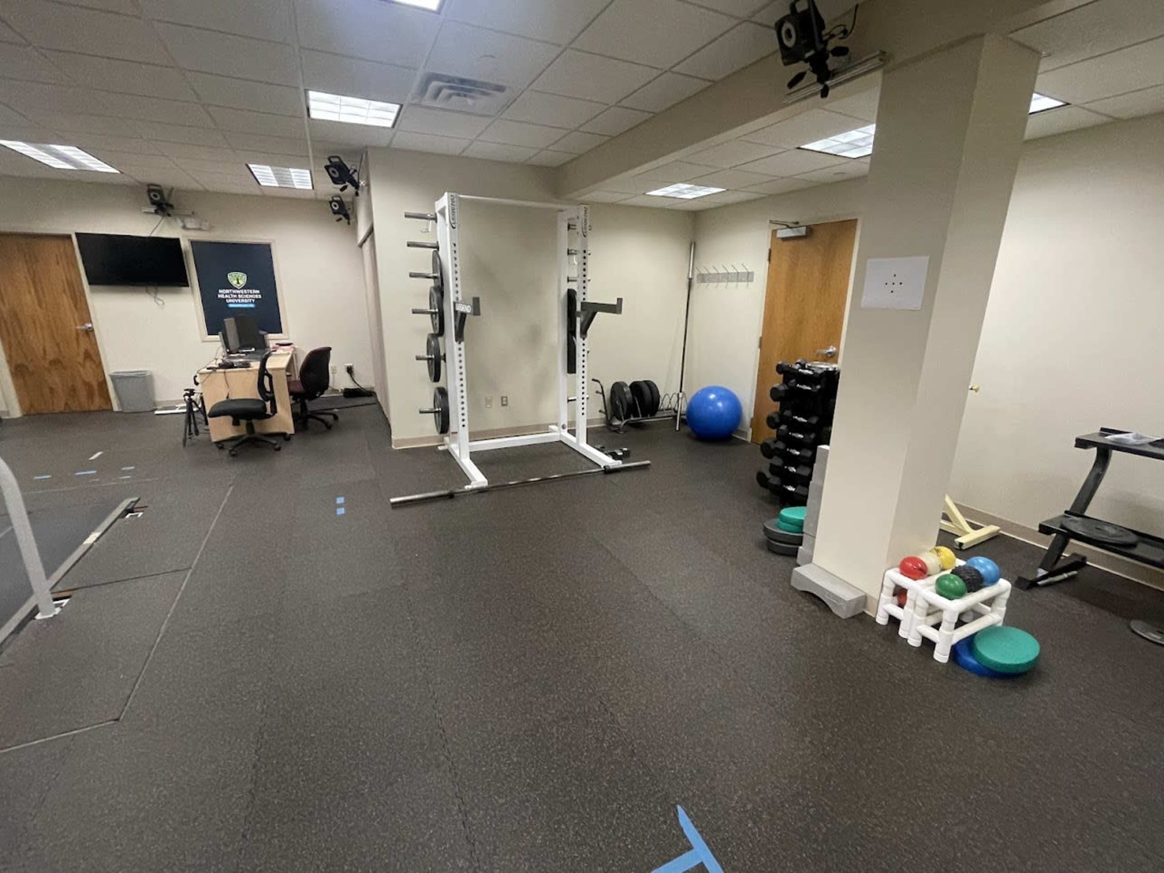 A spacious gym area equipped with weightlifting equipment, exercise balls, and free weights.