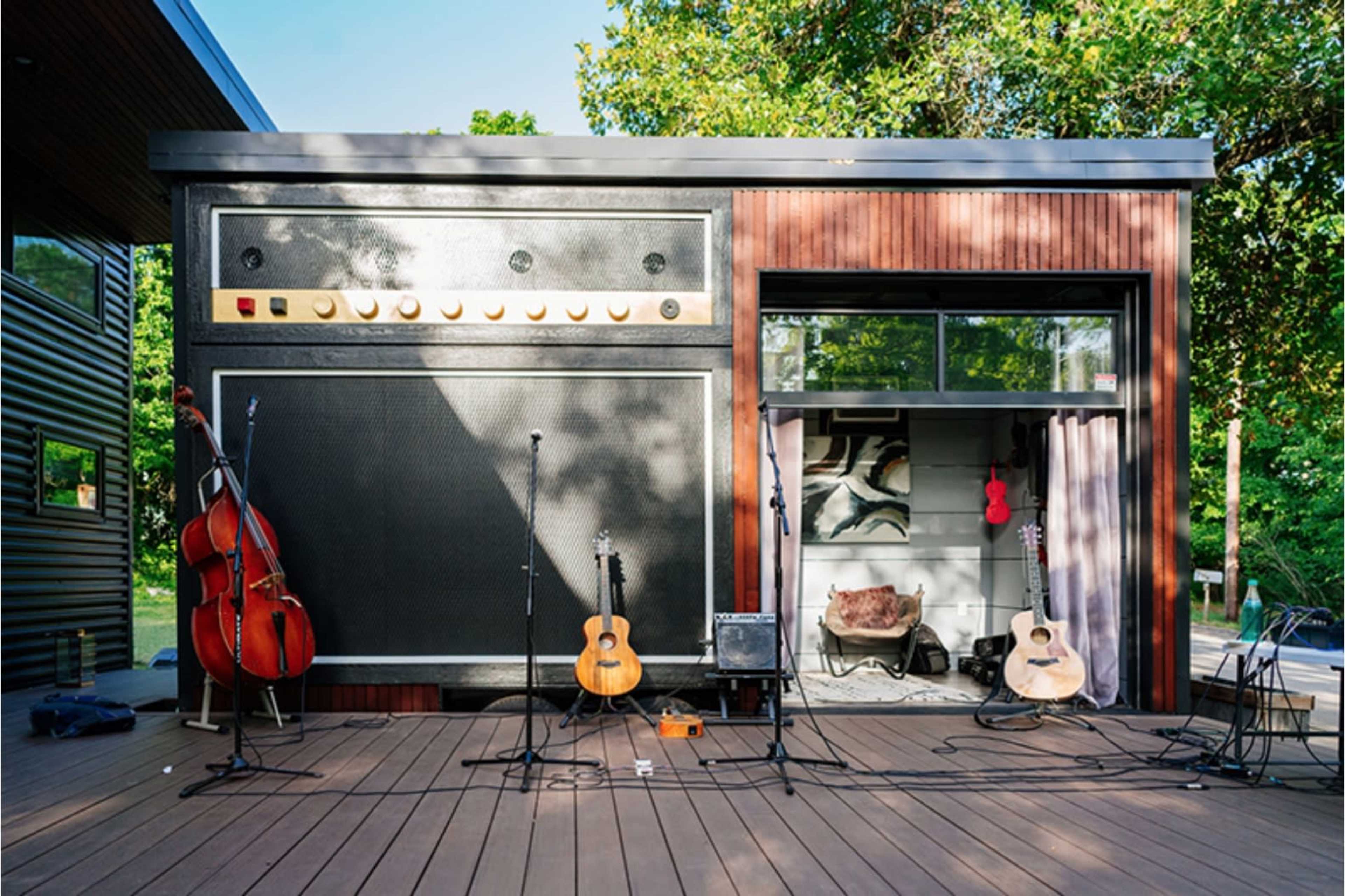 A small music stage with multiple instruments, including guitars and a double bass, set against a backdrop designed to resemble a large amplifier.