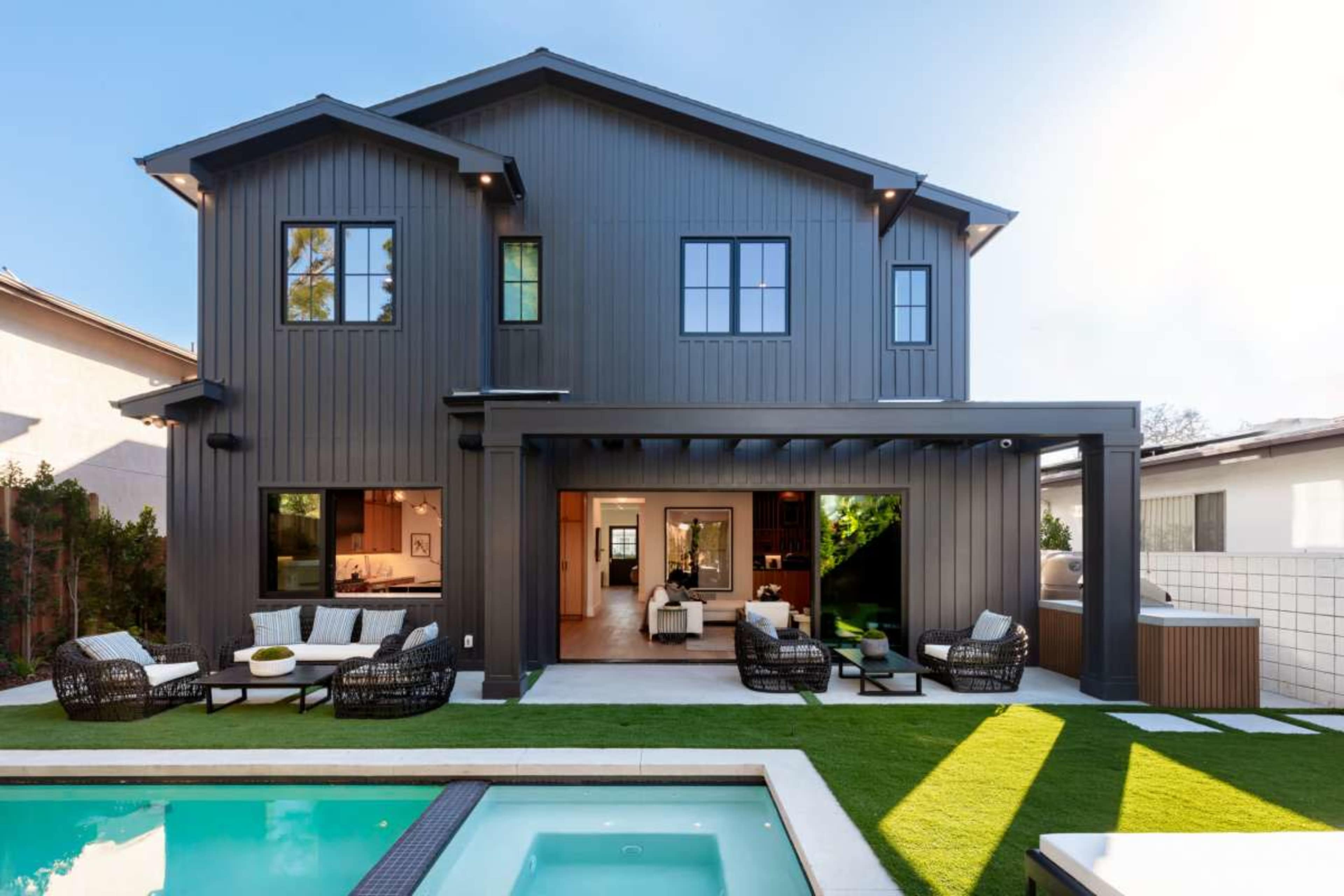 The image shows a modern two-story house with large windows, a backyard pool, and outdoor seating areas.