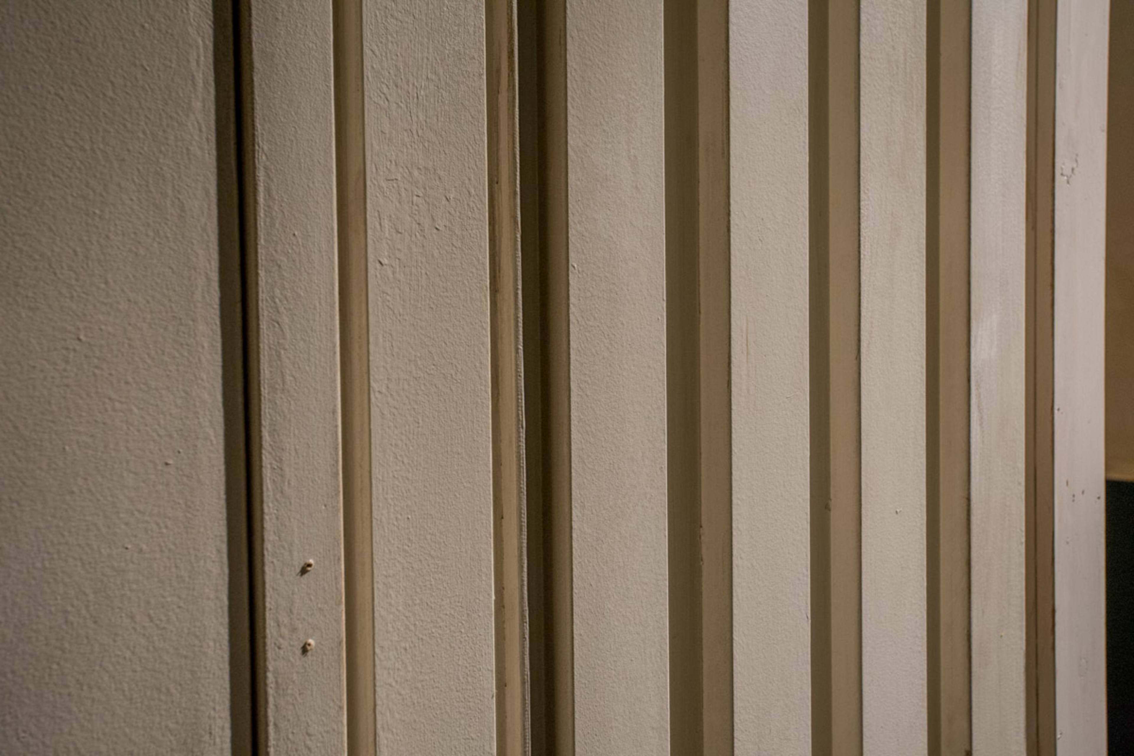 A section of a wall with vertical paneling and a textured finish.