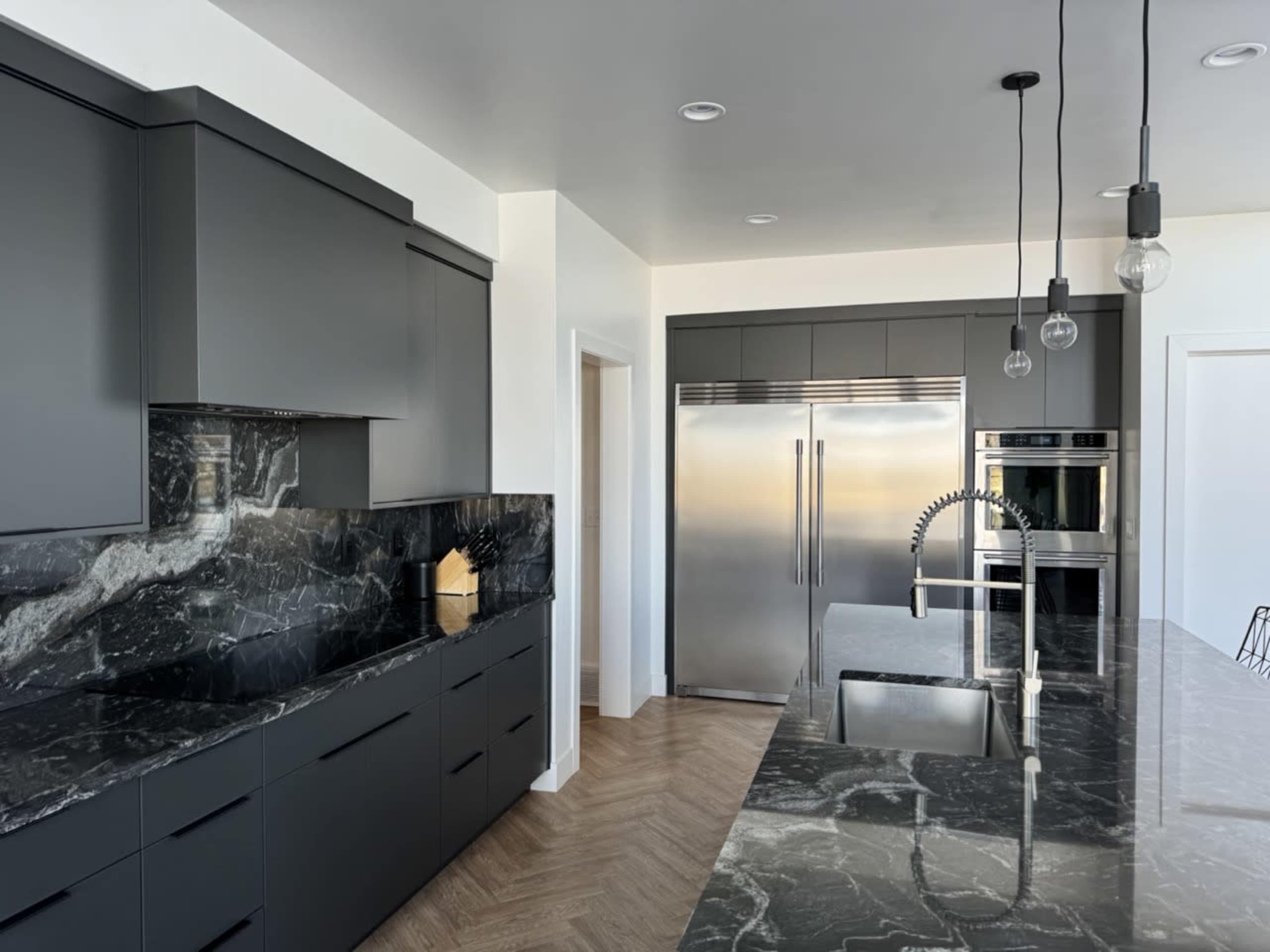 The modern kitchen features sleek black cabinetry and marble countertops, with stainless steel appliances and pendant lighting.
