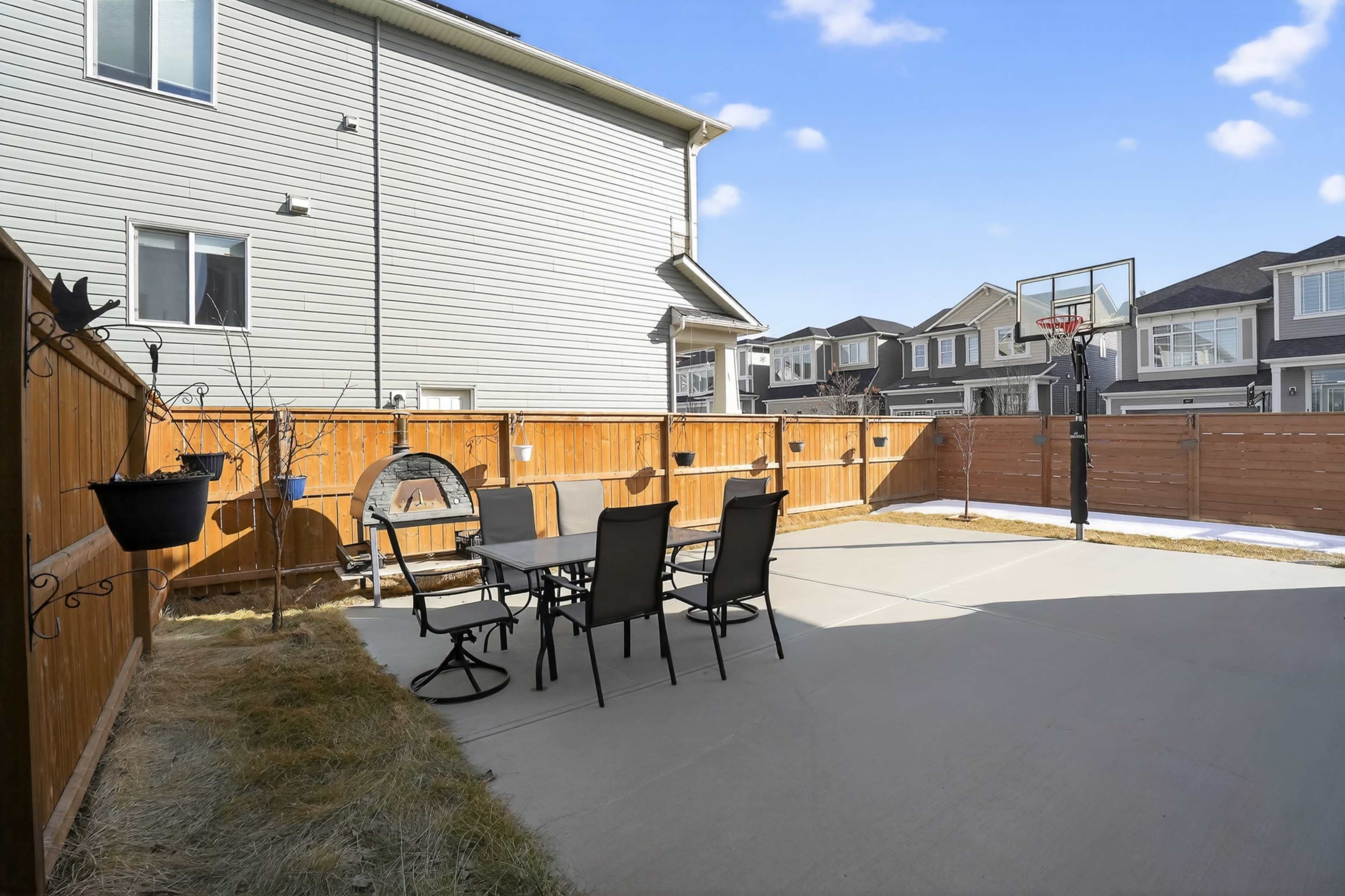 The image shows a spacious patio area with outdoor furniture and a basketball hoop in a residential backyard.