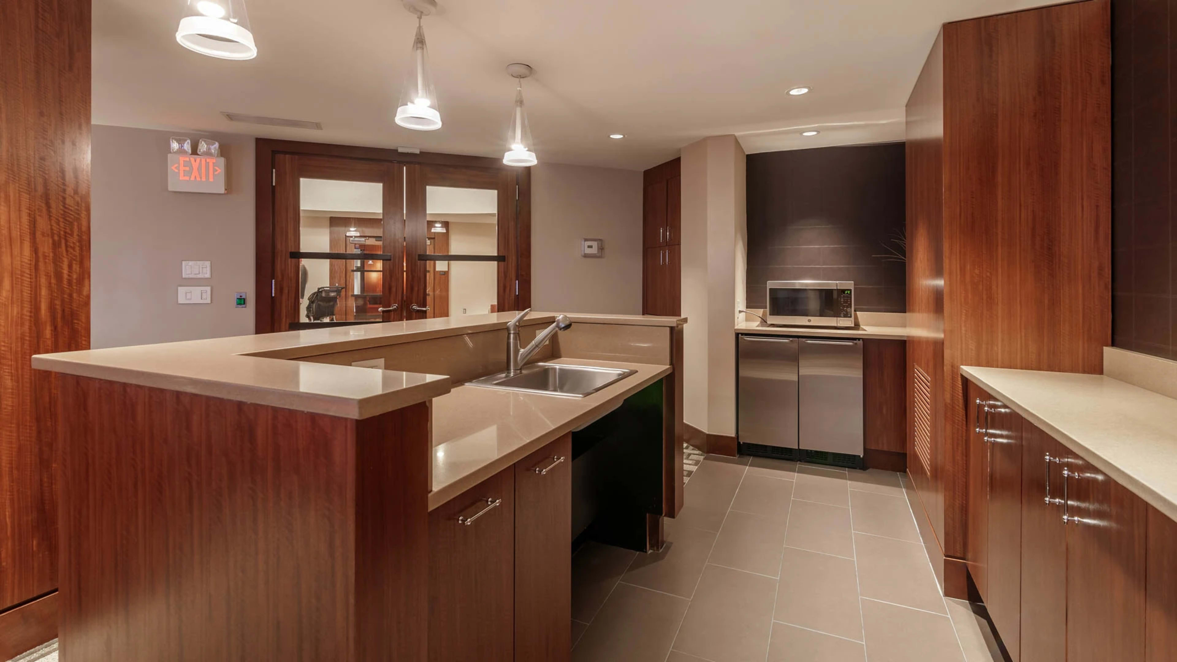 The image shows a modern kitchen with wooden cabinets, a gray countertop, and stainless steel appliances.