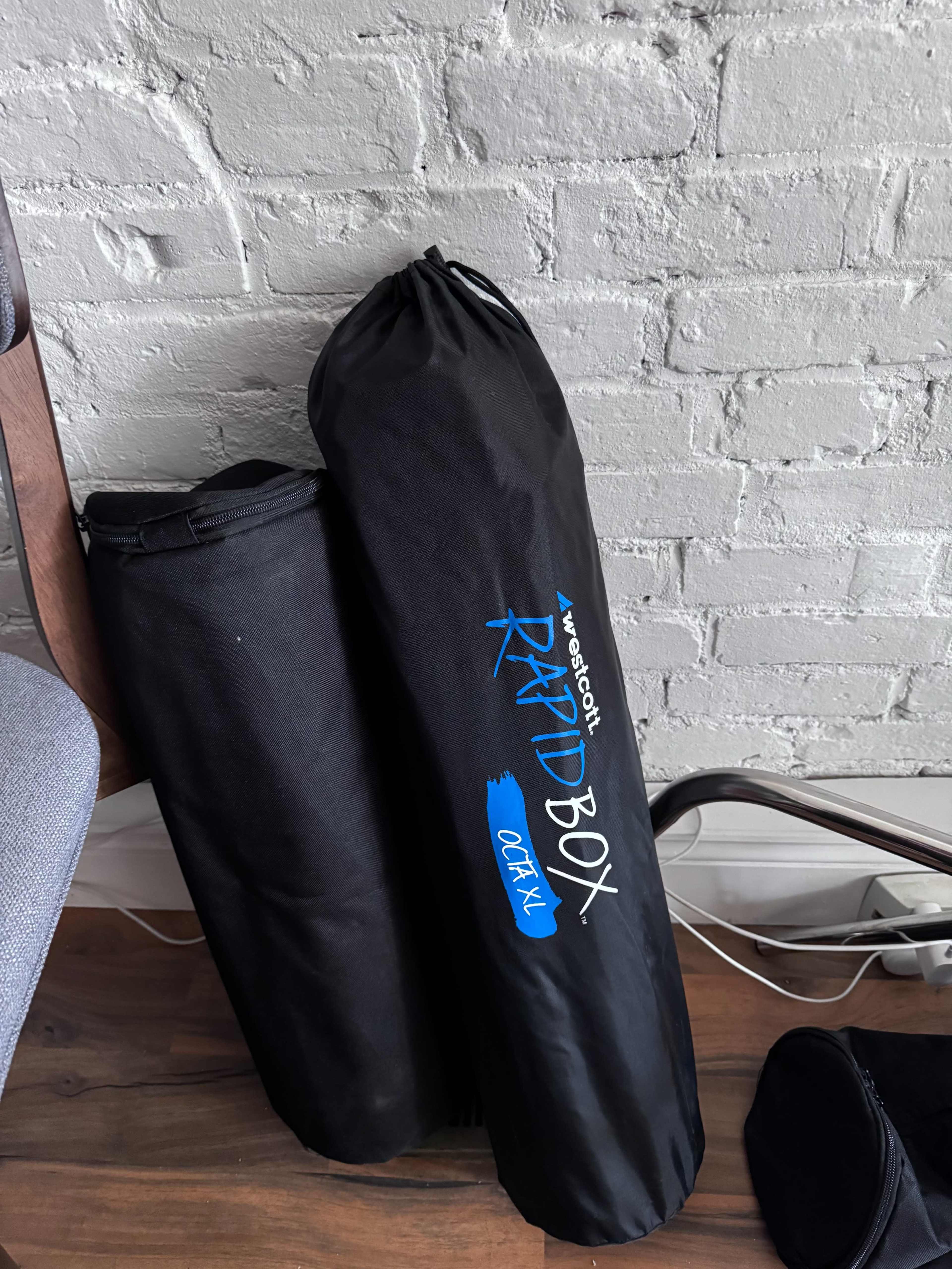 The image shows two black bags leaning against a white brick wall, one labeled "RAIDBOX" and the other unmarked.