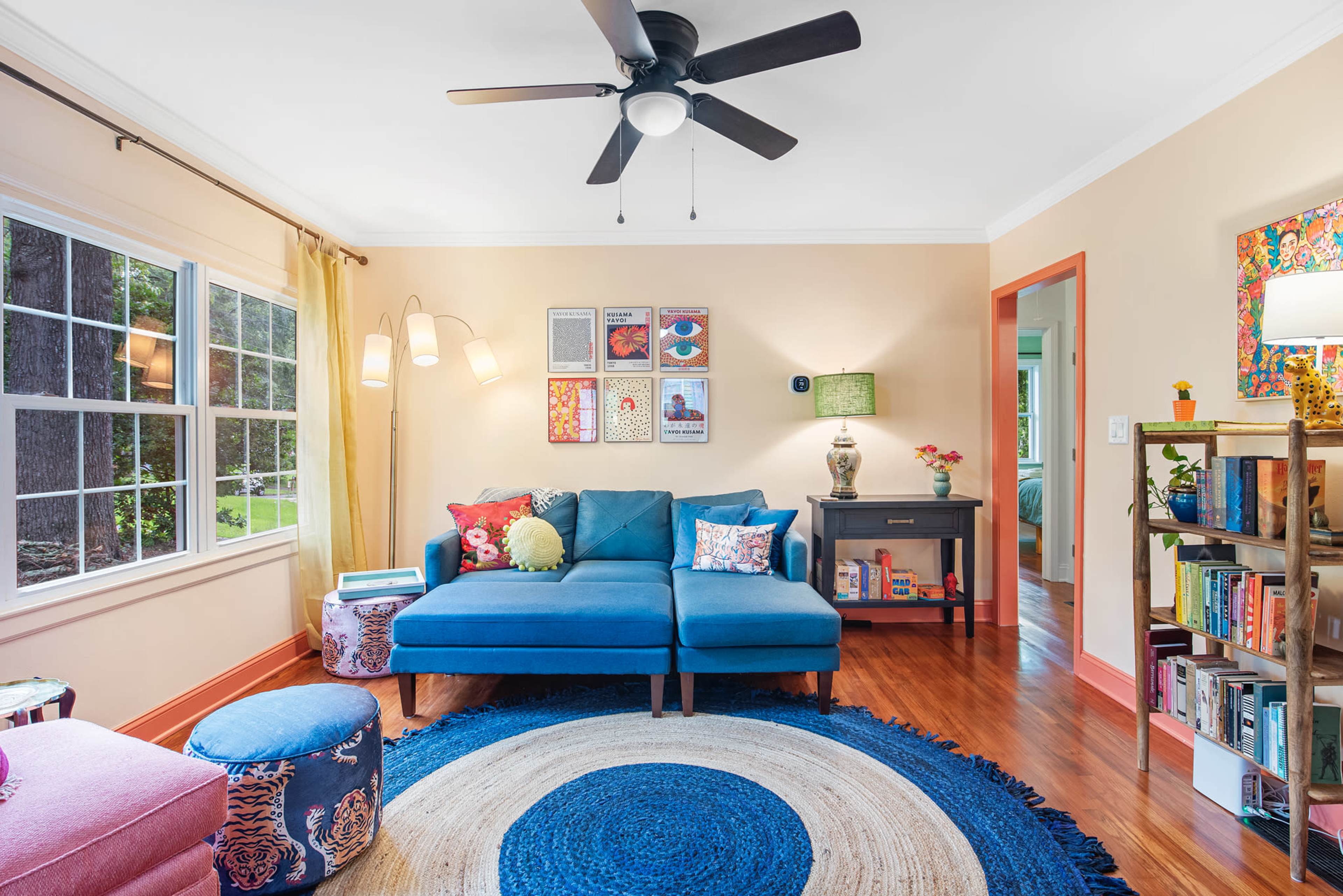 A cozy living room featuring a blue sectional sofa, a round area rug, and a window with natural light.