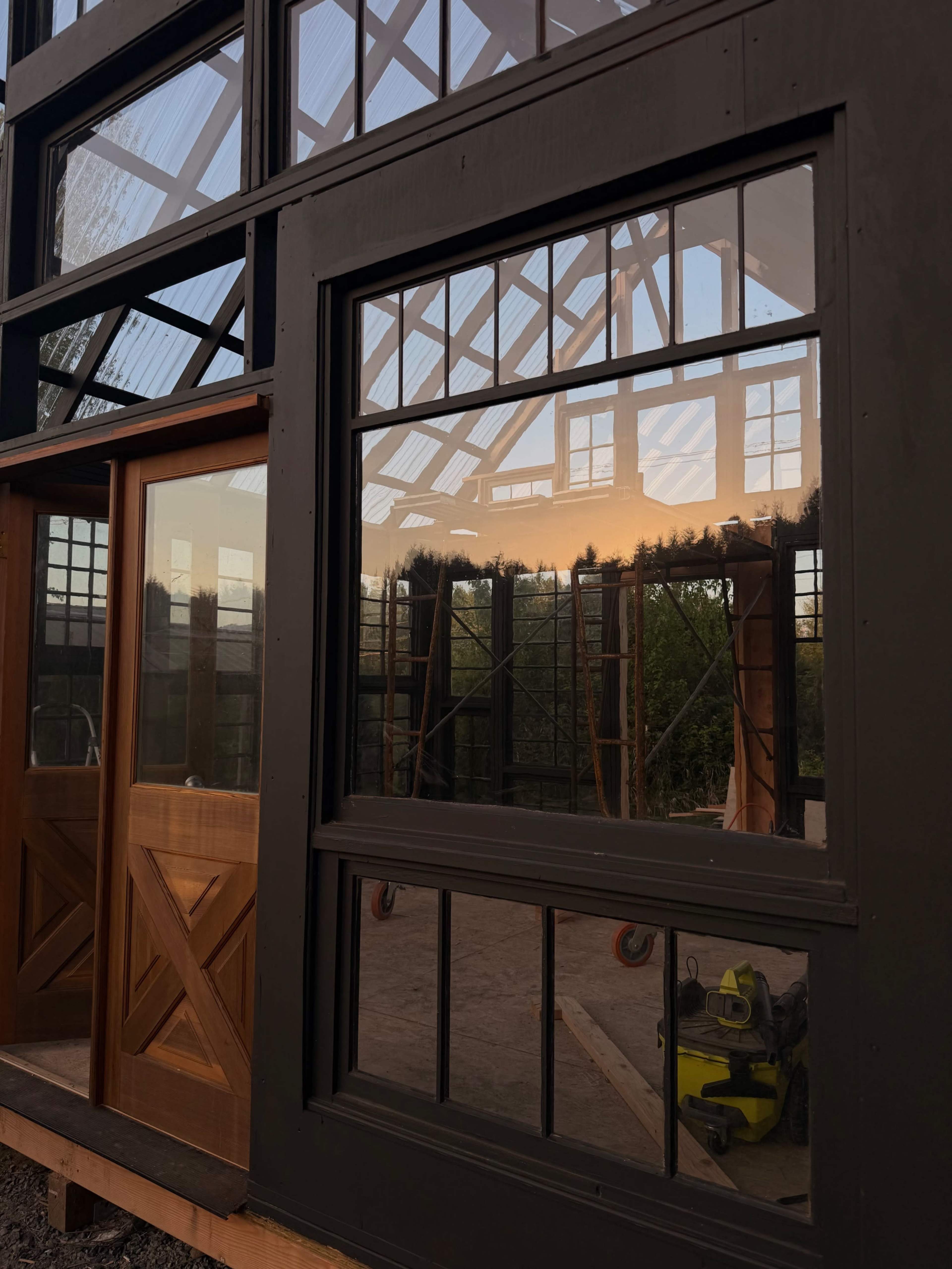 The image shows a building frame with large glass windows reflecting a sunset.
