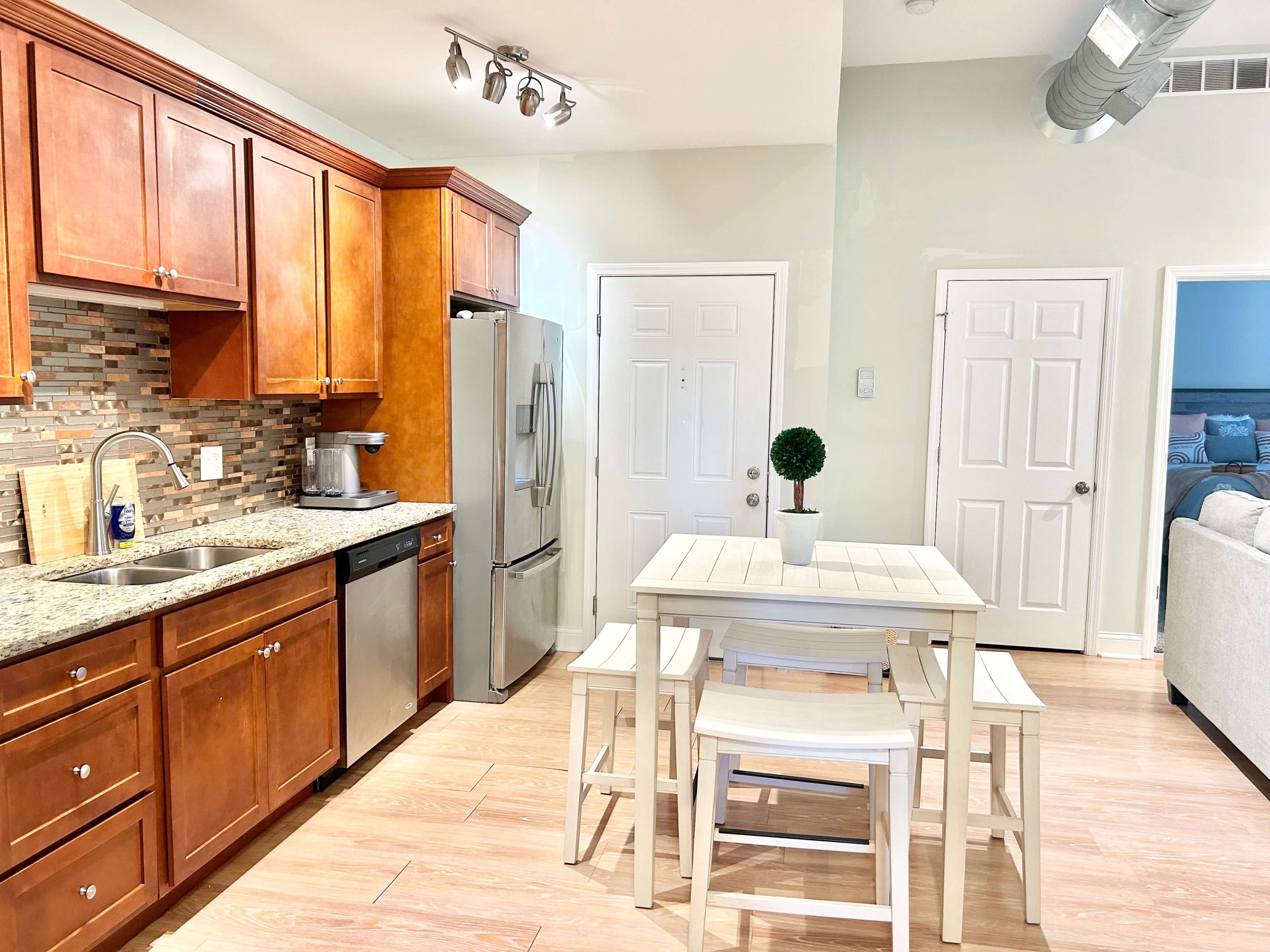 A modern kitchen with wooden cabinets, stainless steel appliances, and a small dining table set for four.