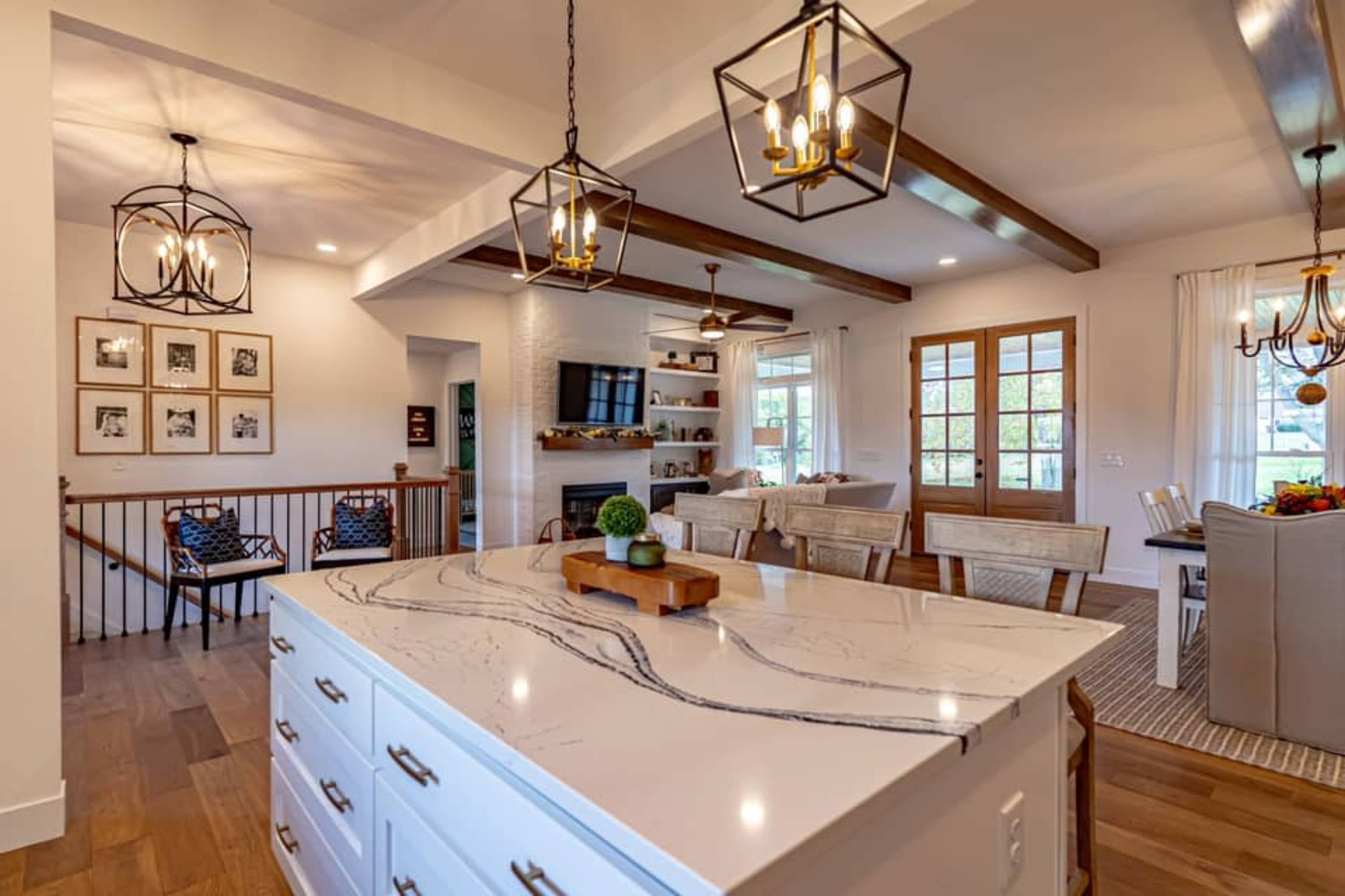 A modern kitchen and living area with a large island, wooden beams, and a cozy seating arrangement.