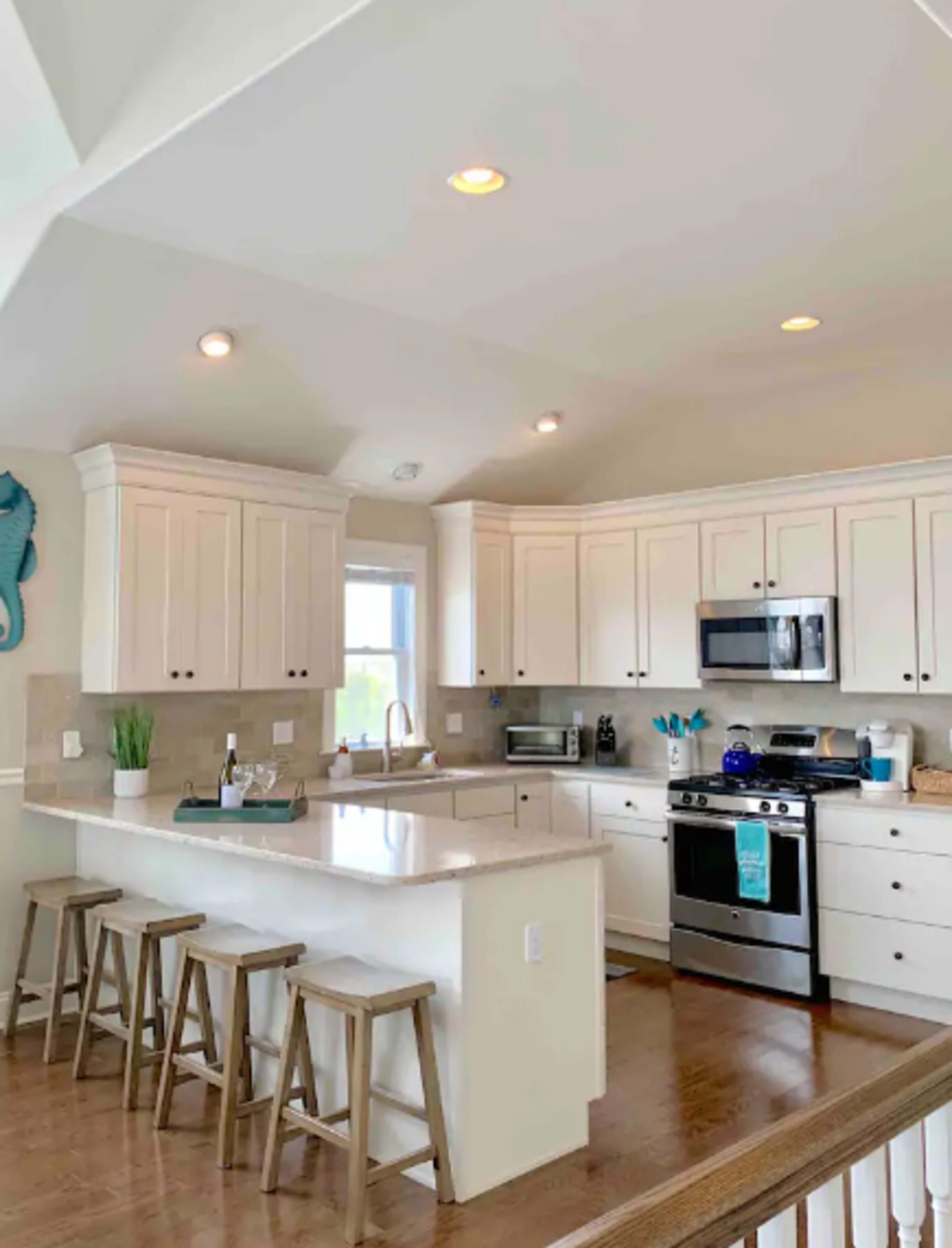 A modern kitchen featuring white cabinetry, a large island with bar stools, and stainless steel appliances.