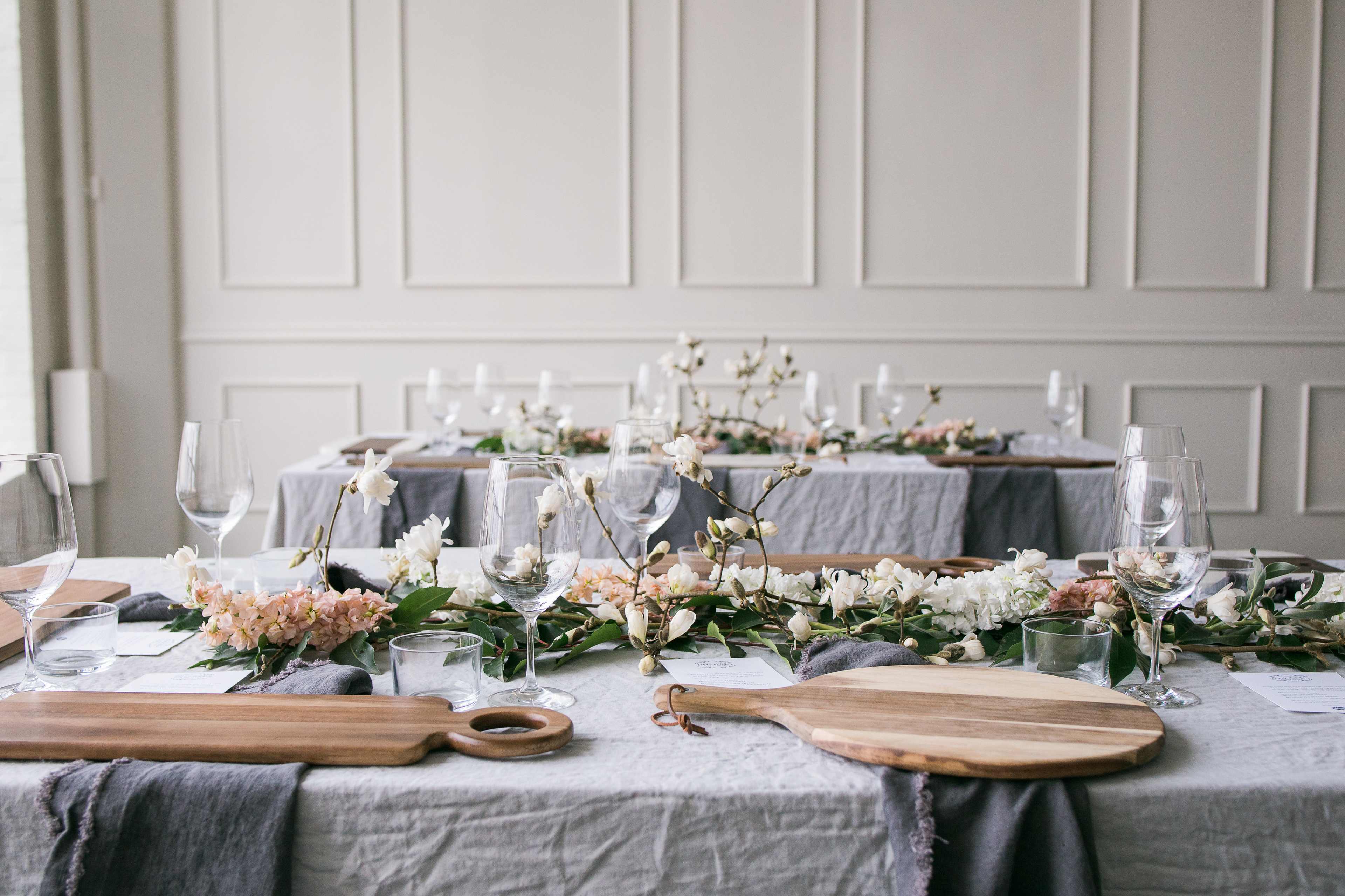A elegantly set dining table with floral arrangements and wooden serving boards.