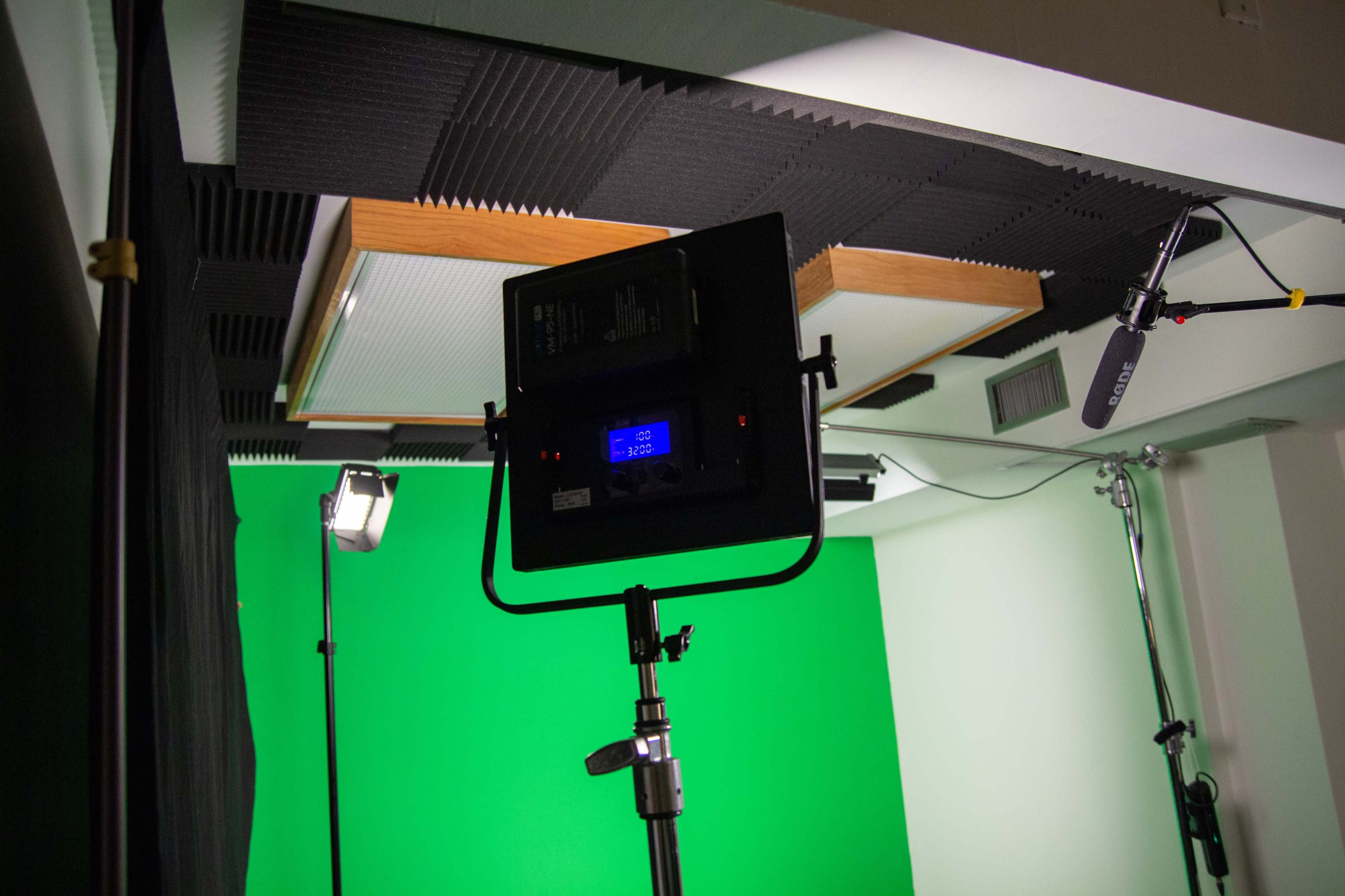 A green screen setup in a studio with various lighting and sound equipment positioned around.
