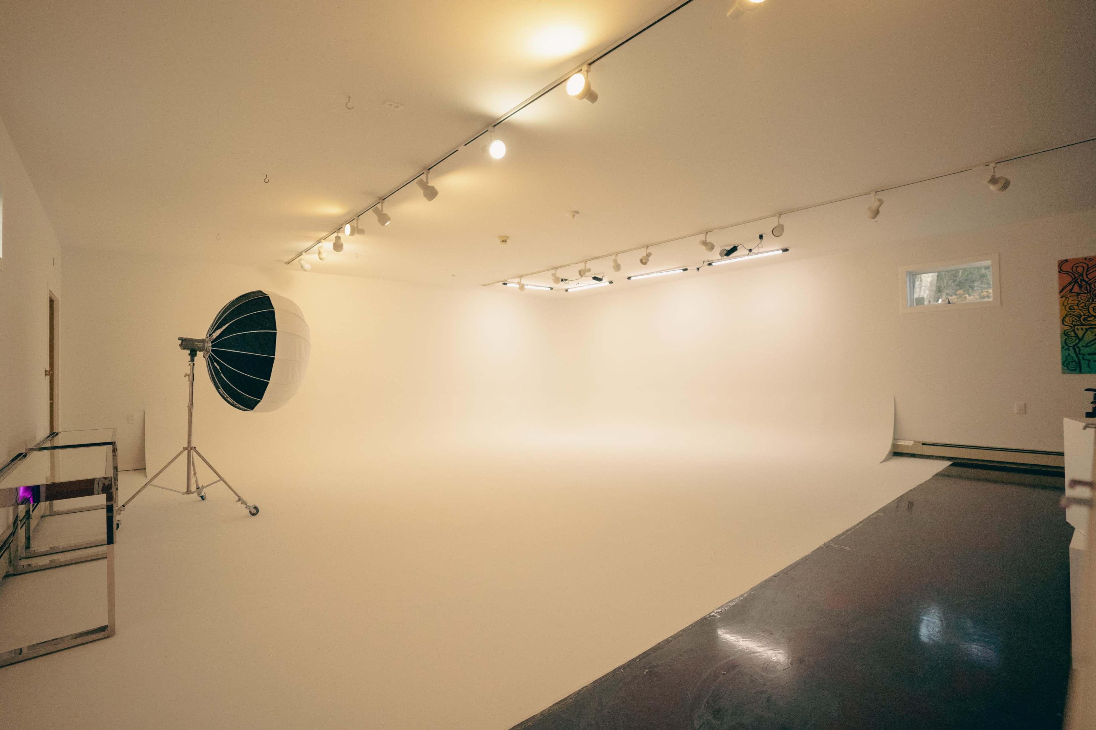 A spacious, well-lit photography studio with a large softbox and a seamless white backdrop.