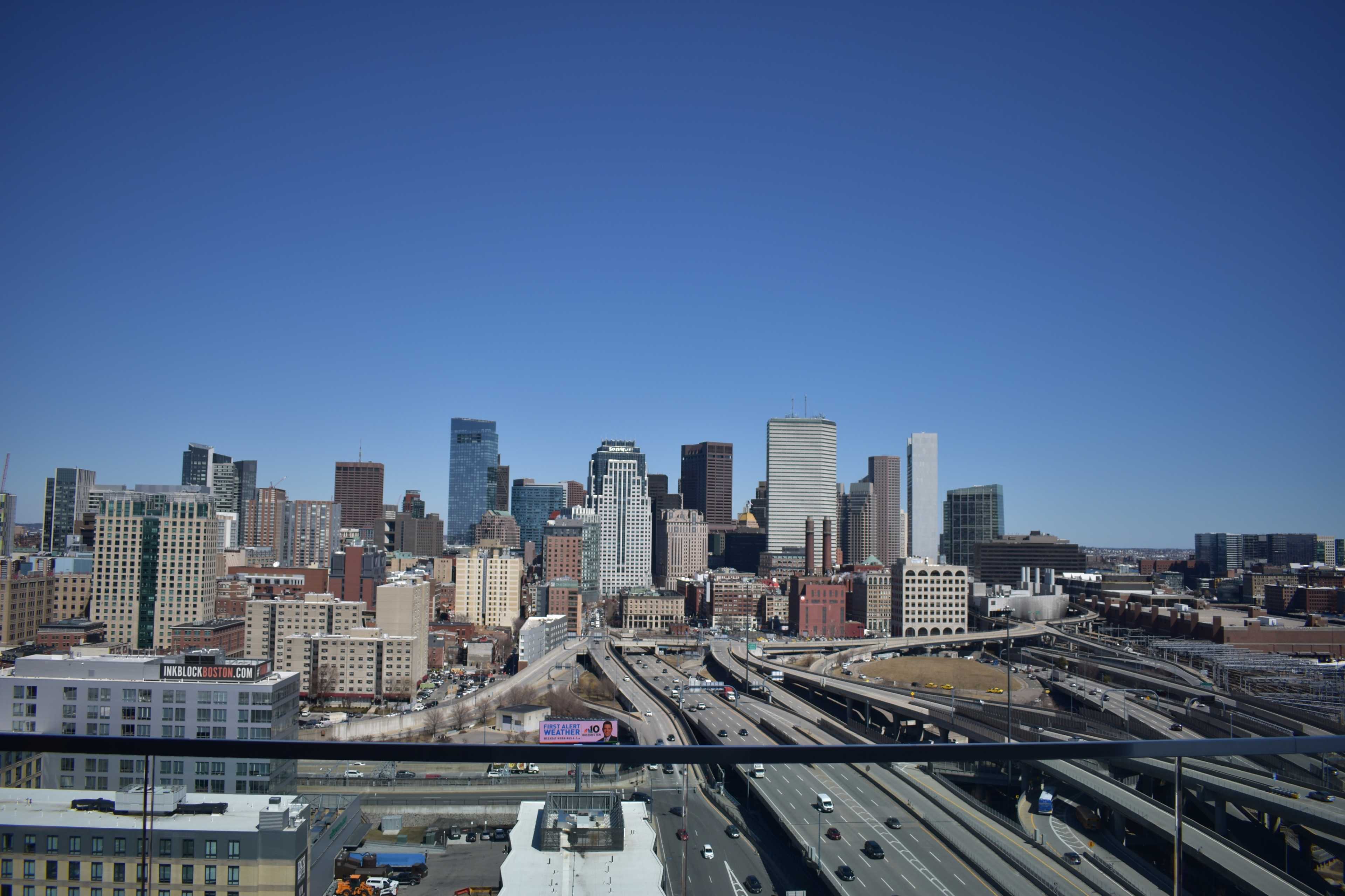 A clear view of a city skyline featuring modern skyscrapers and highways under a blue sky.