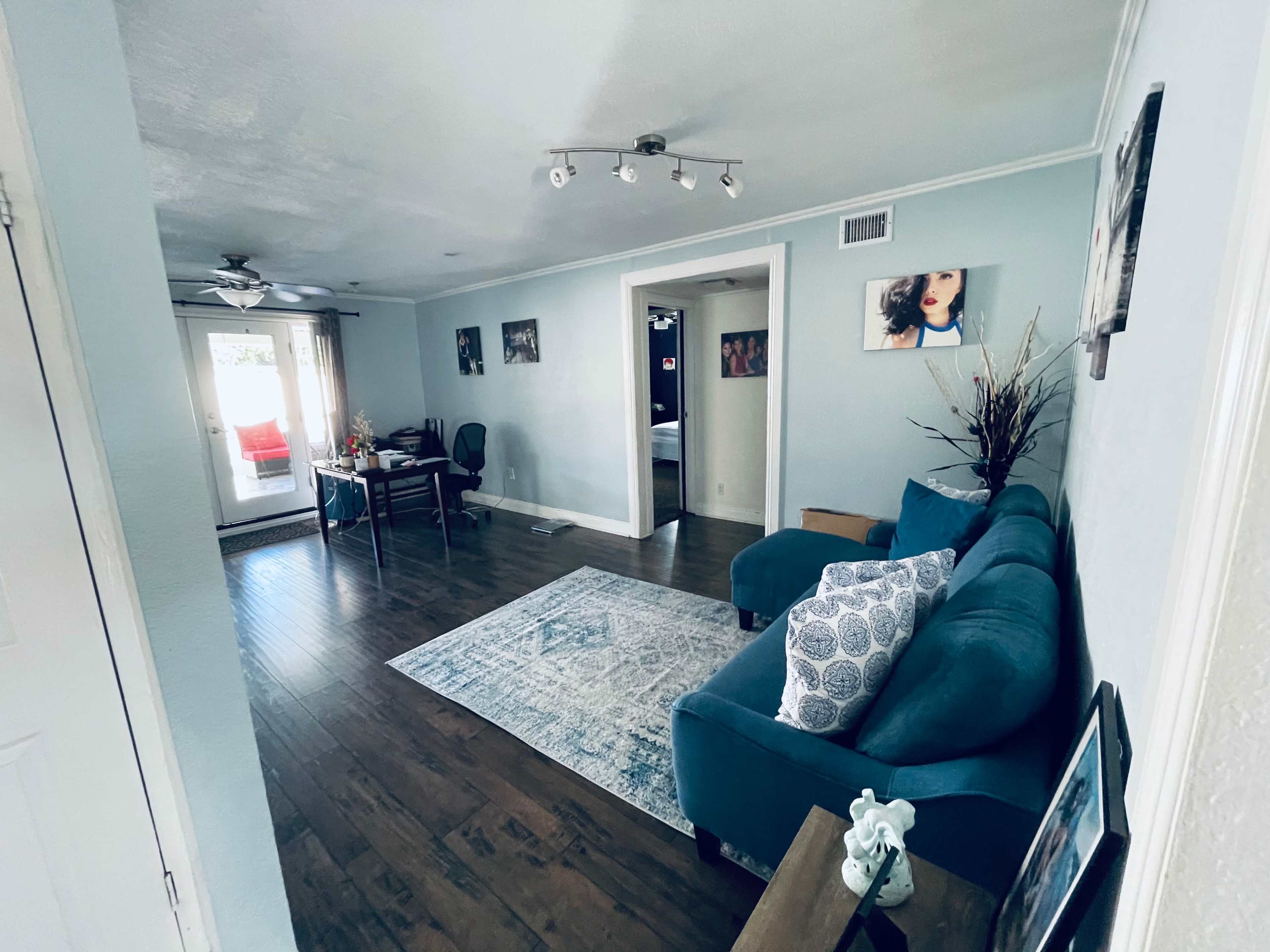 A living room with teal furniture, a dining area, and a door leading to an outdoor space.