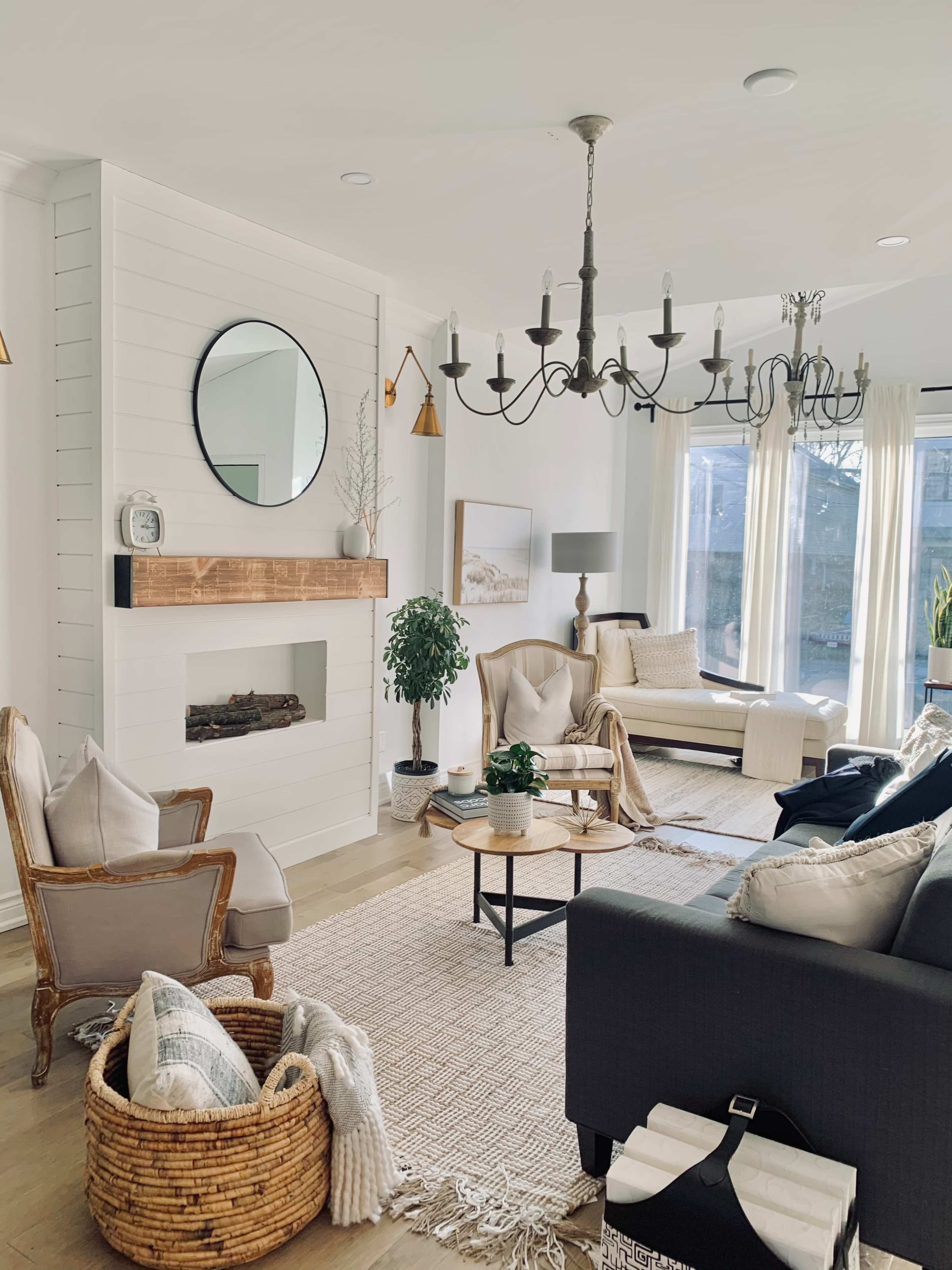 A modern living room with a fireplace, large windows, and a mix of comfortable seating arrangements.