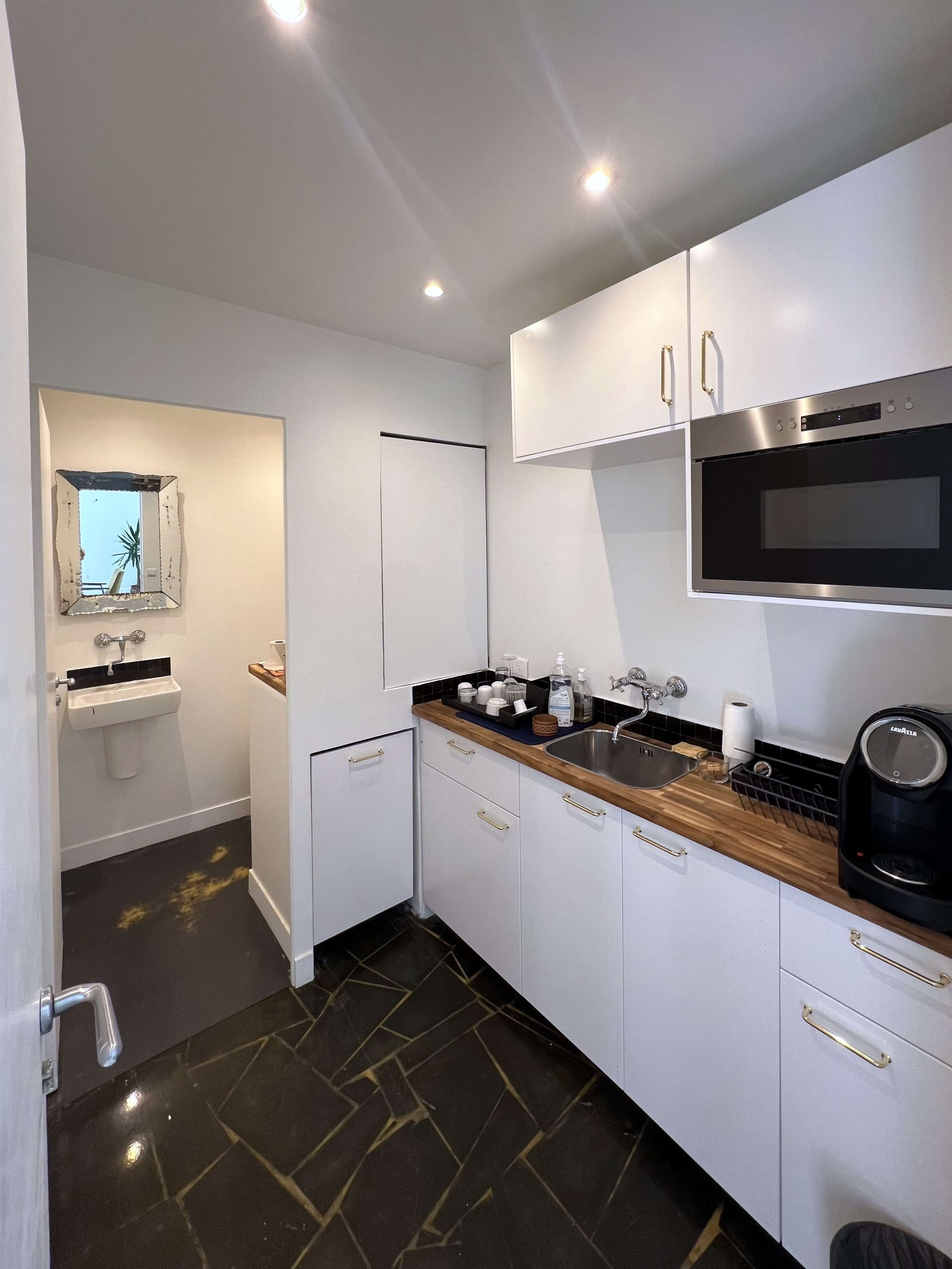 A modern kitchen with white cabinets, a black countertop, and an oven built into the cabinetry.