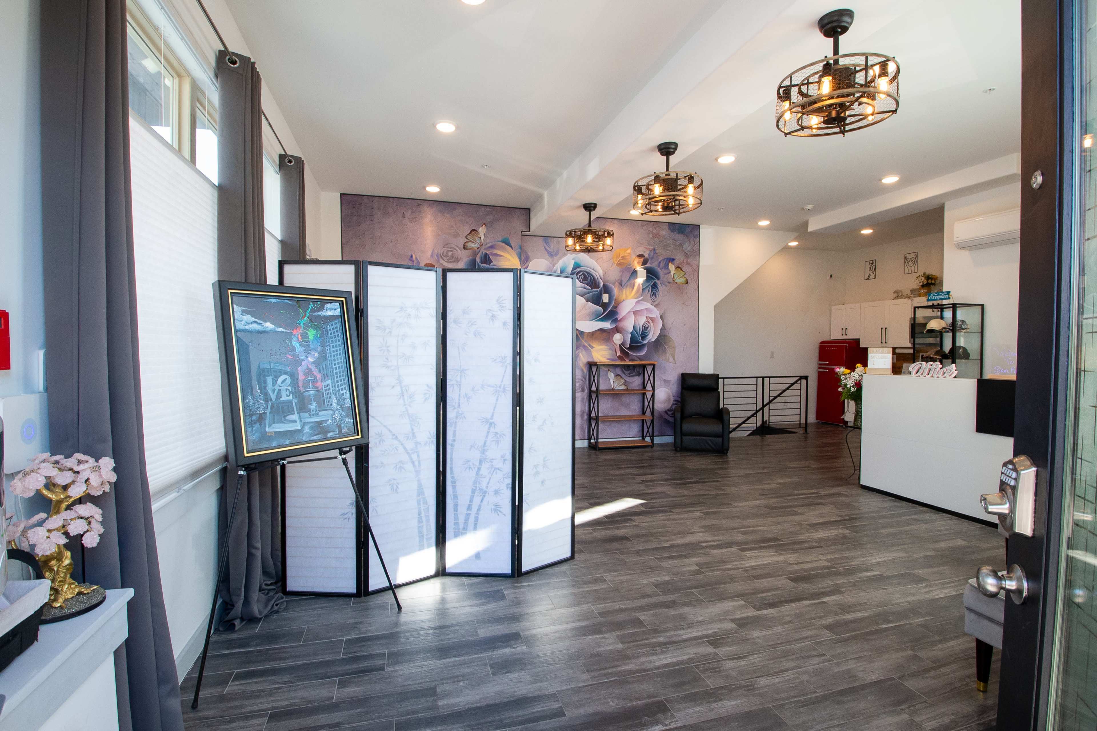 A modern reception area featuring a decorative partition, artwork on the wall, and a front desk with seating arrangements.