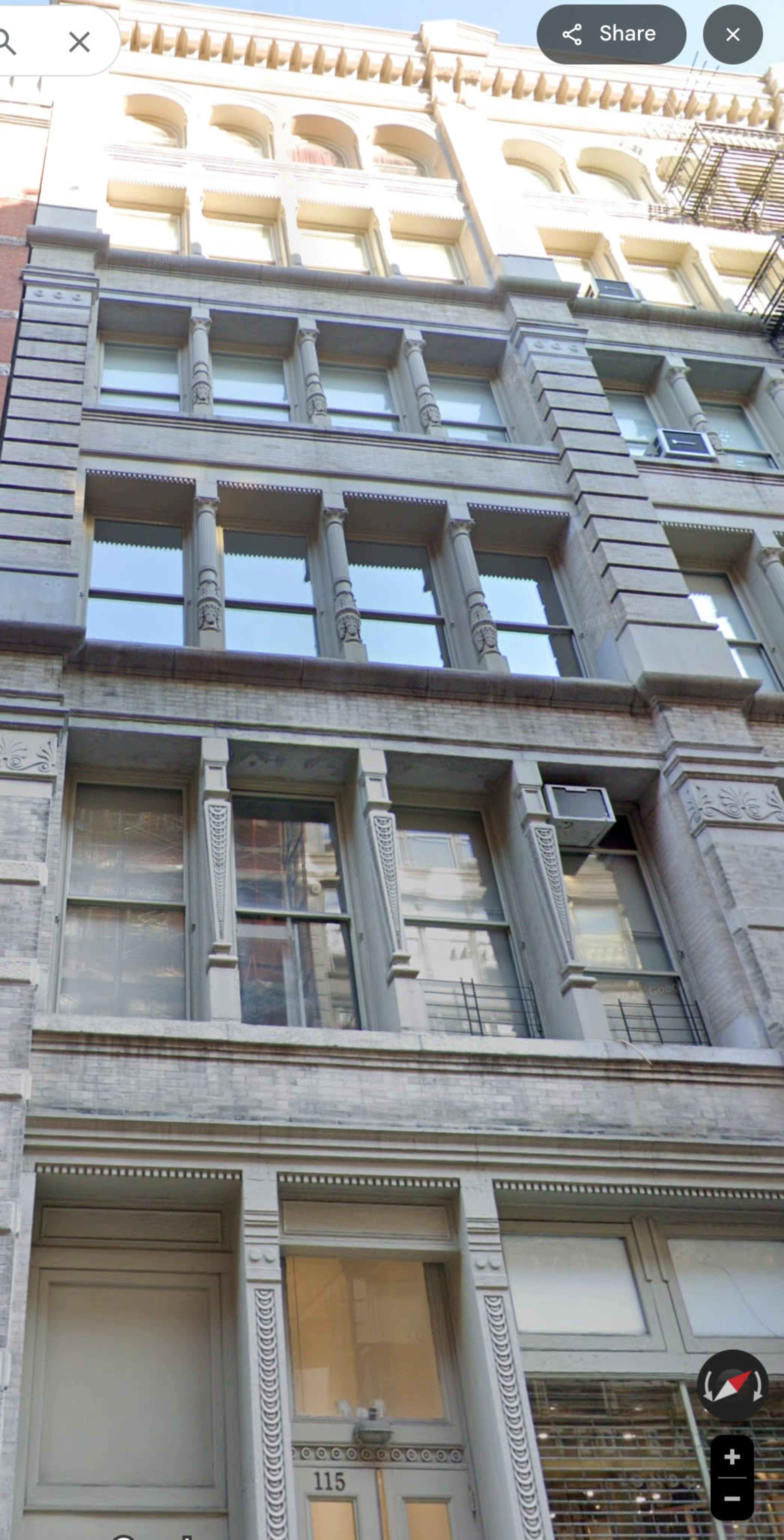 The image shows a historic commercial building with ornate architectural details, featuring large windows and decorative column-like elements.