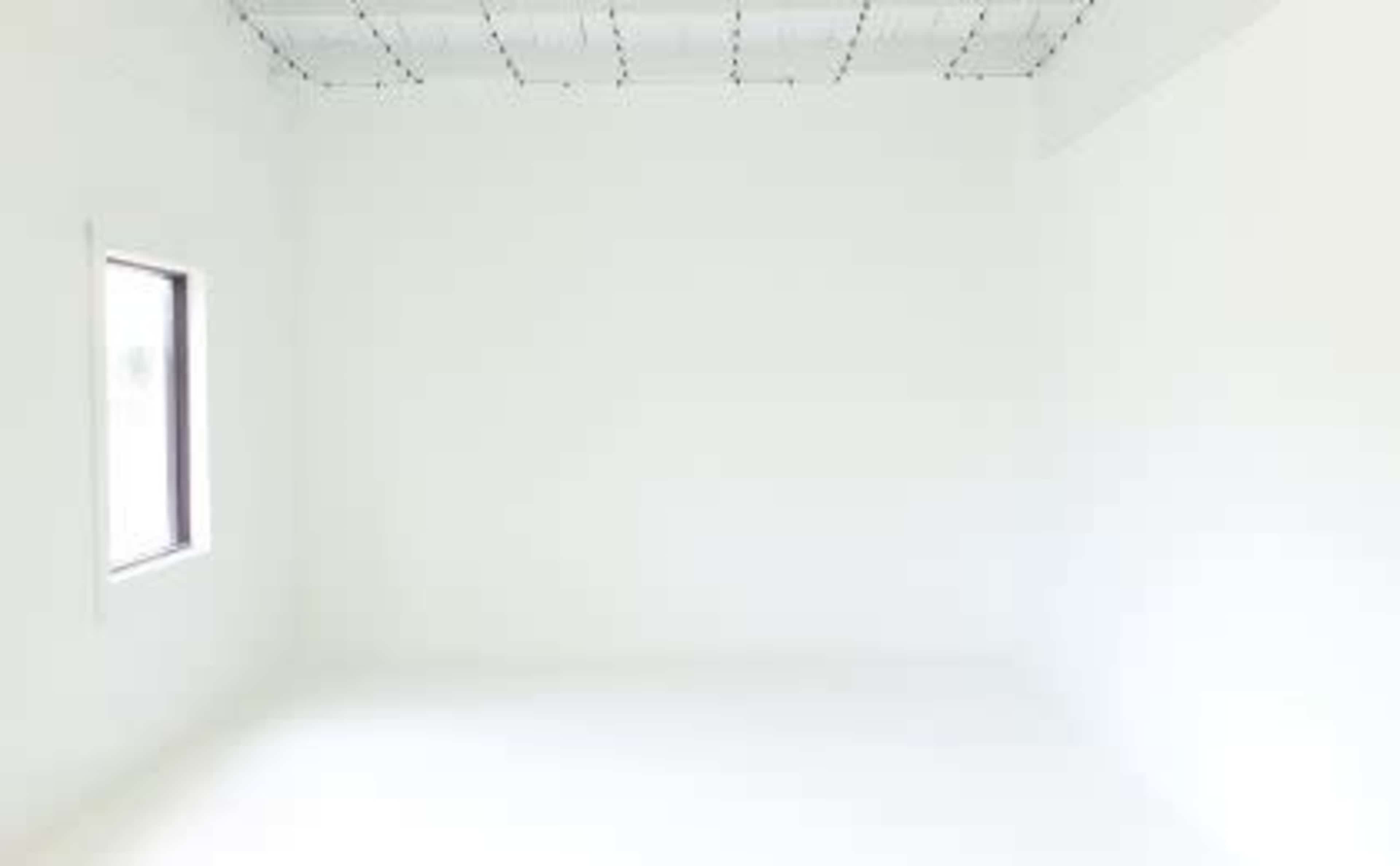An empty white room with a single window on one wall.