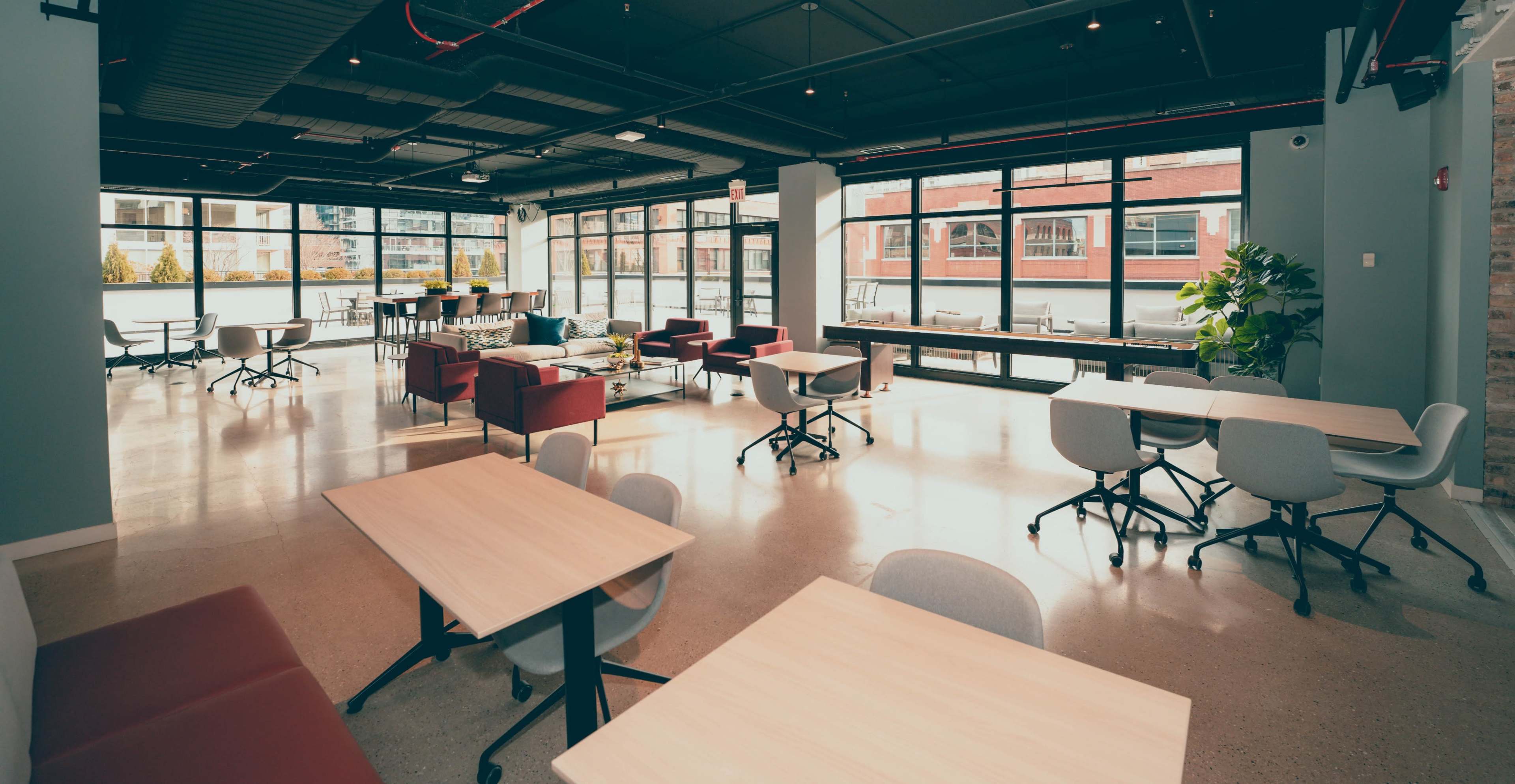 A spacious, modern interior with large windows, featuring various seating areas and tables.