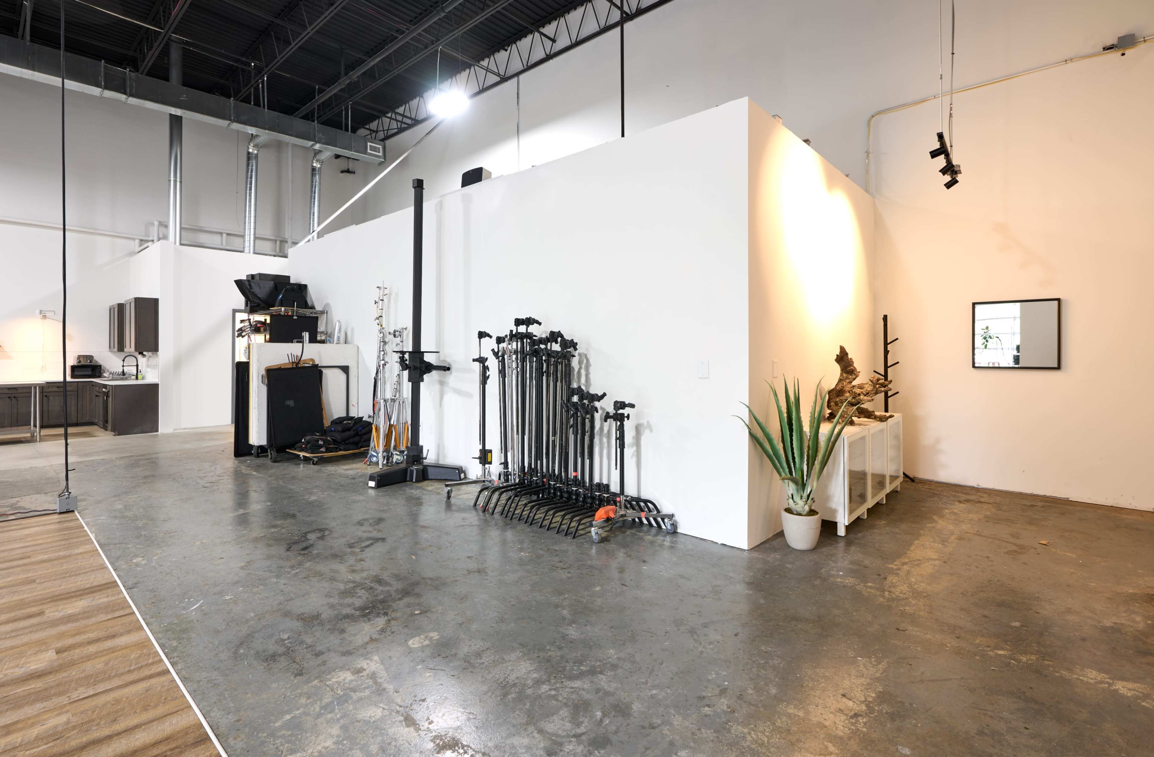 The image shows an industrial-style interior space with polished concrete floors, a wall featuring equipment, and a decorative plant in a white pot.