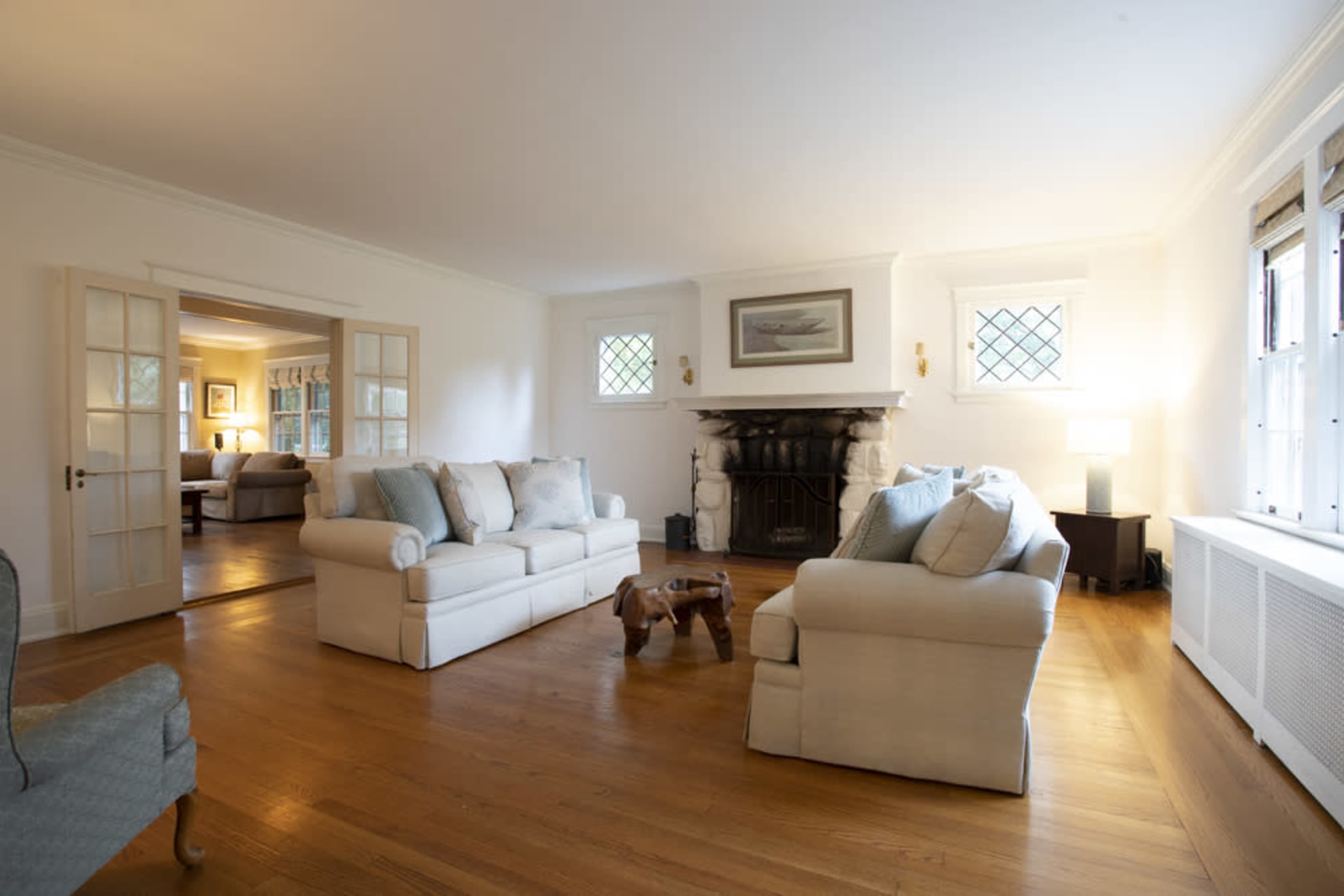 A living room with a light-colored sofa and armchair, a wooden coffee table in the center, and a fireplace on one wall.