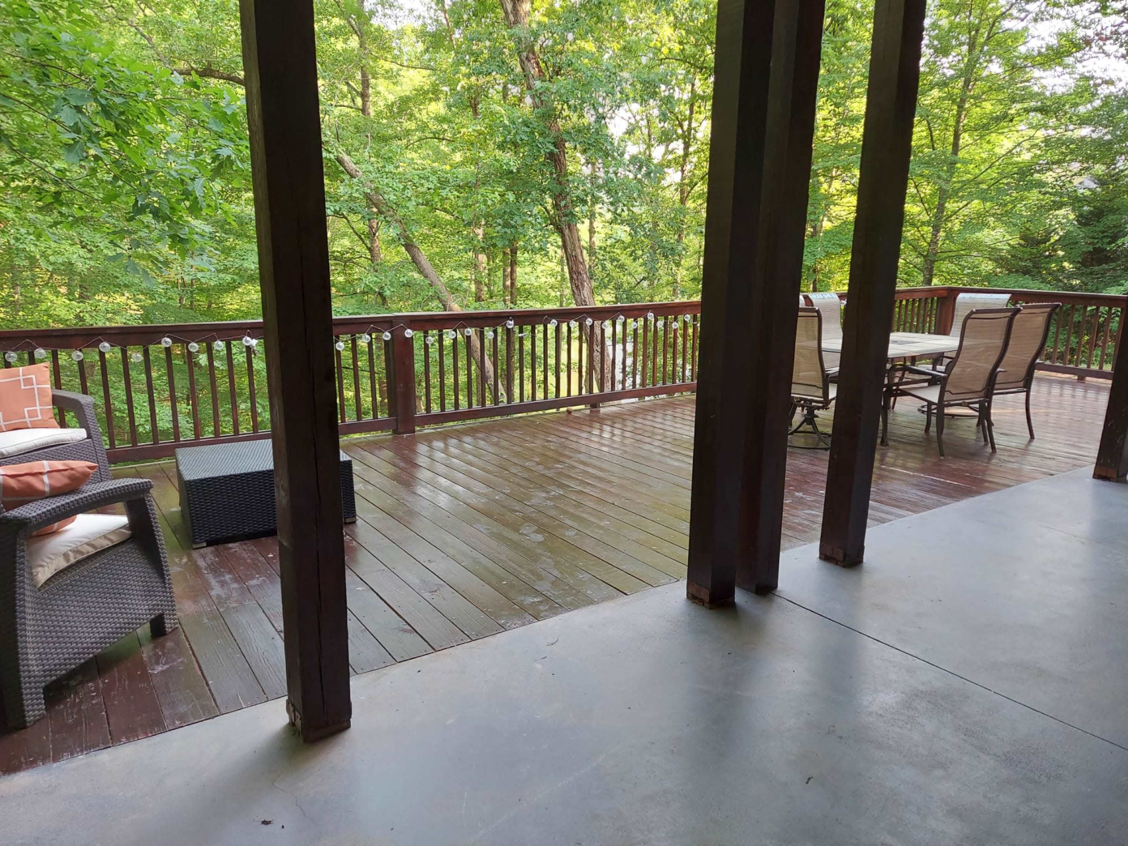 A spacious wooden deck surrounded by greenery, featuring outdoor furniture and a clear view of the forest.