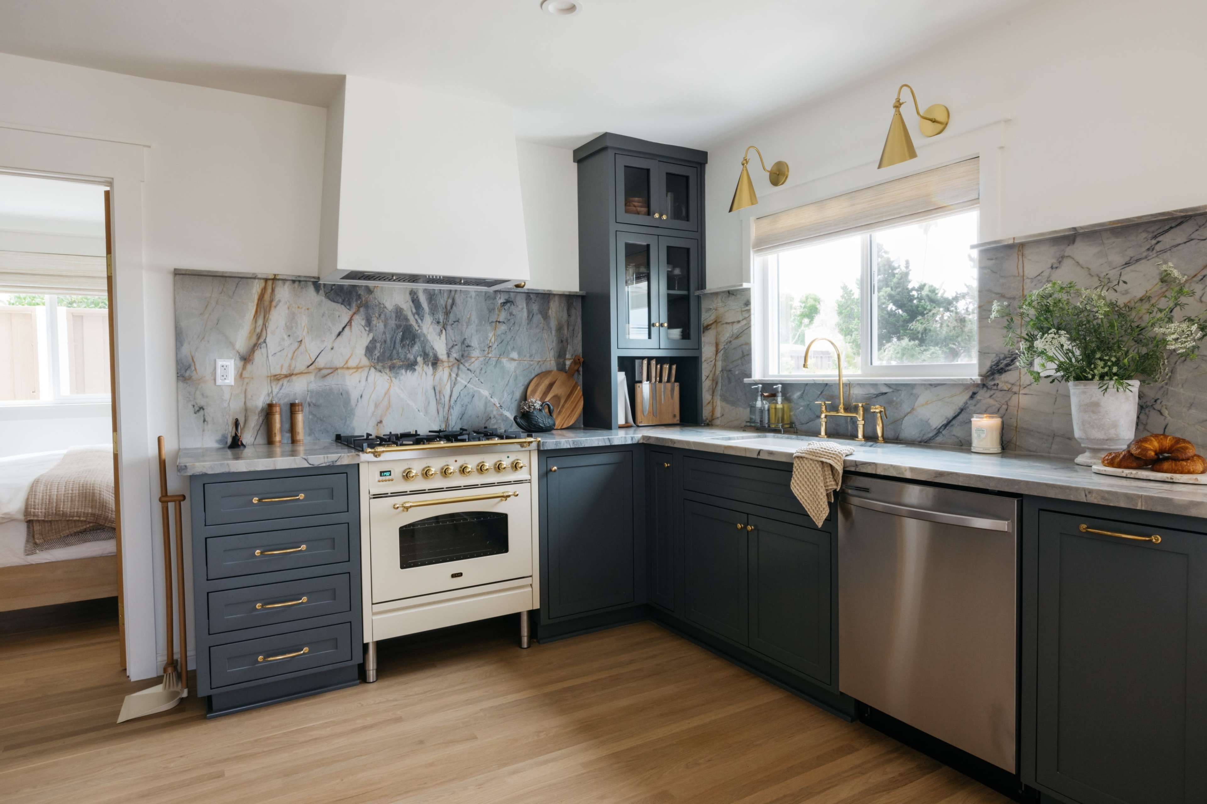 The kitchen features dark blue cabinetry, a marble backsplash, a white stove, and hardwood flooring.